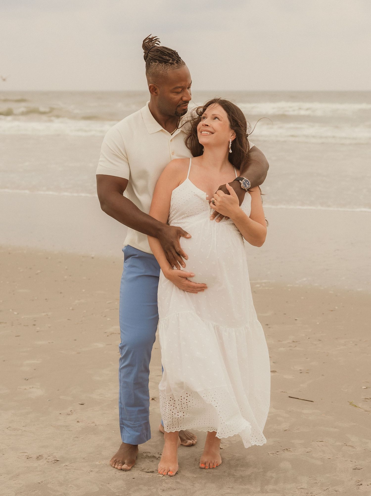 Couple shares intimate moment while sitting on beach at sunset.