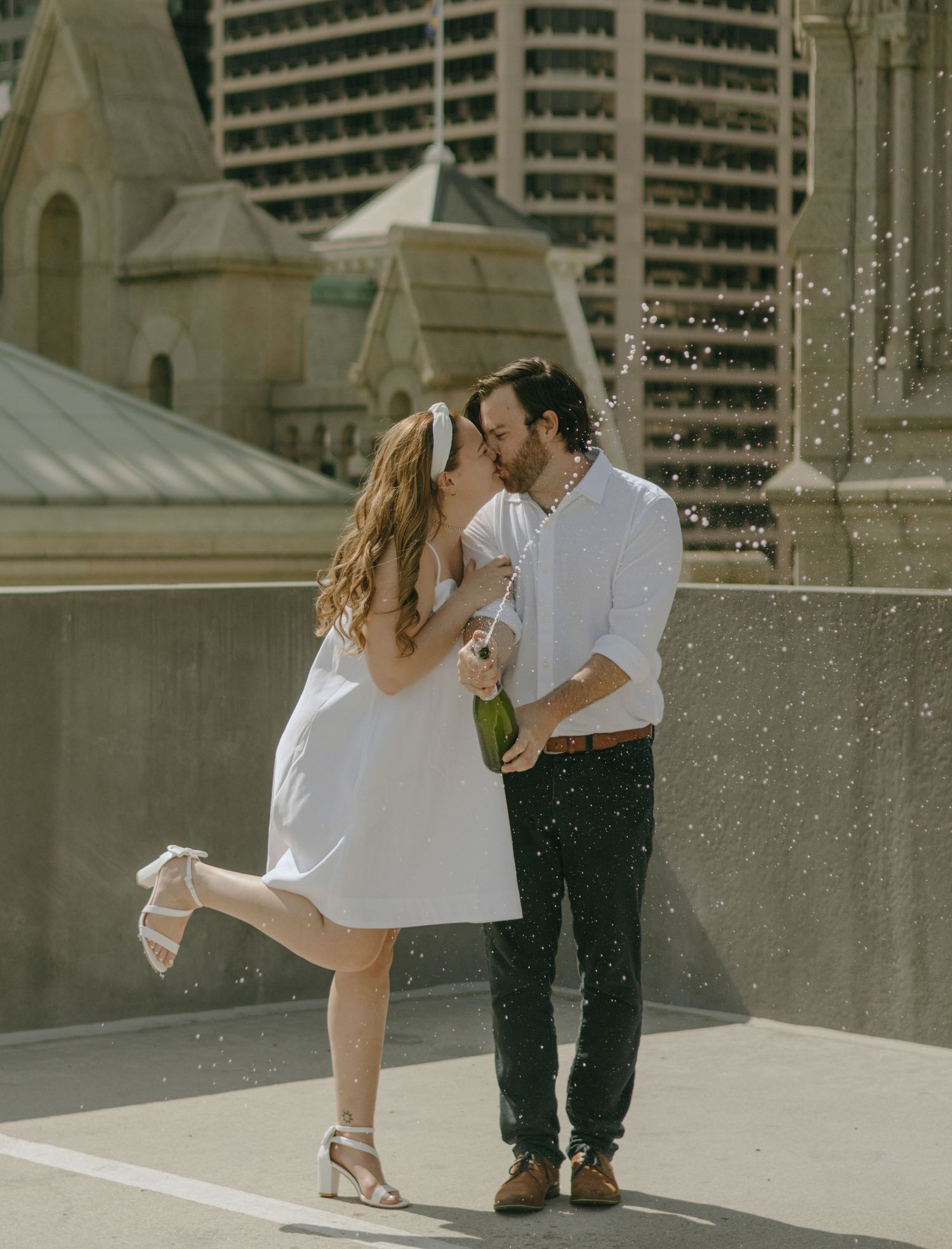 Romantic couple shares tender moments against an urban architectural backdrop in a series of candid photos.