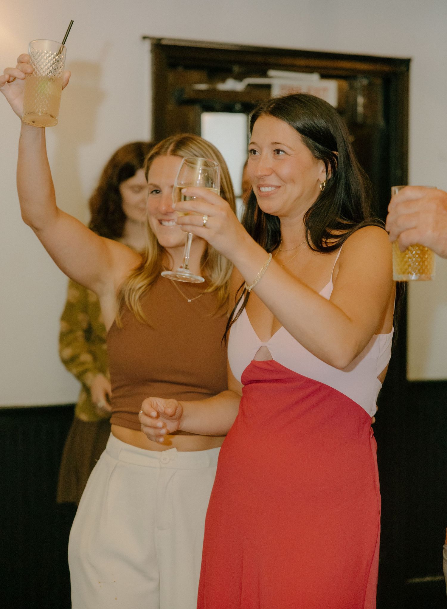 Friends raising glasses in celebration at an indoor party.