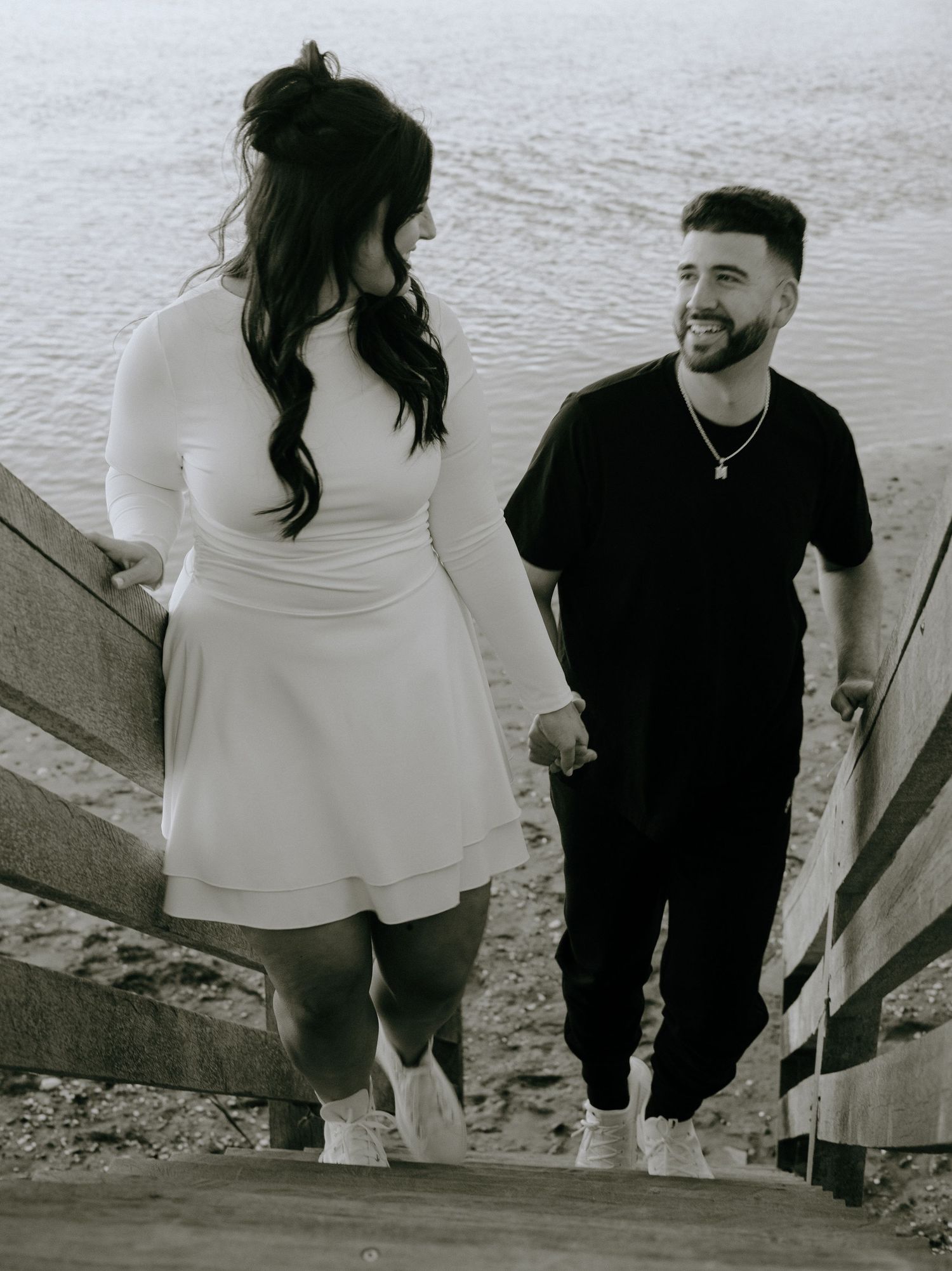 A couple walking together on a beach boardwalk in casual attire.
