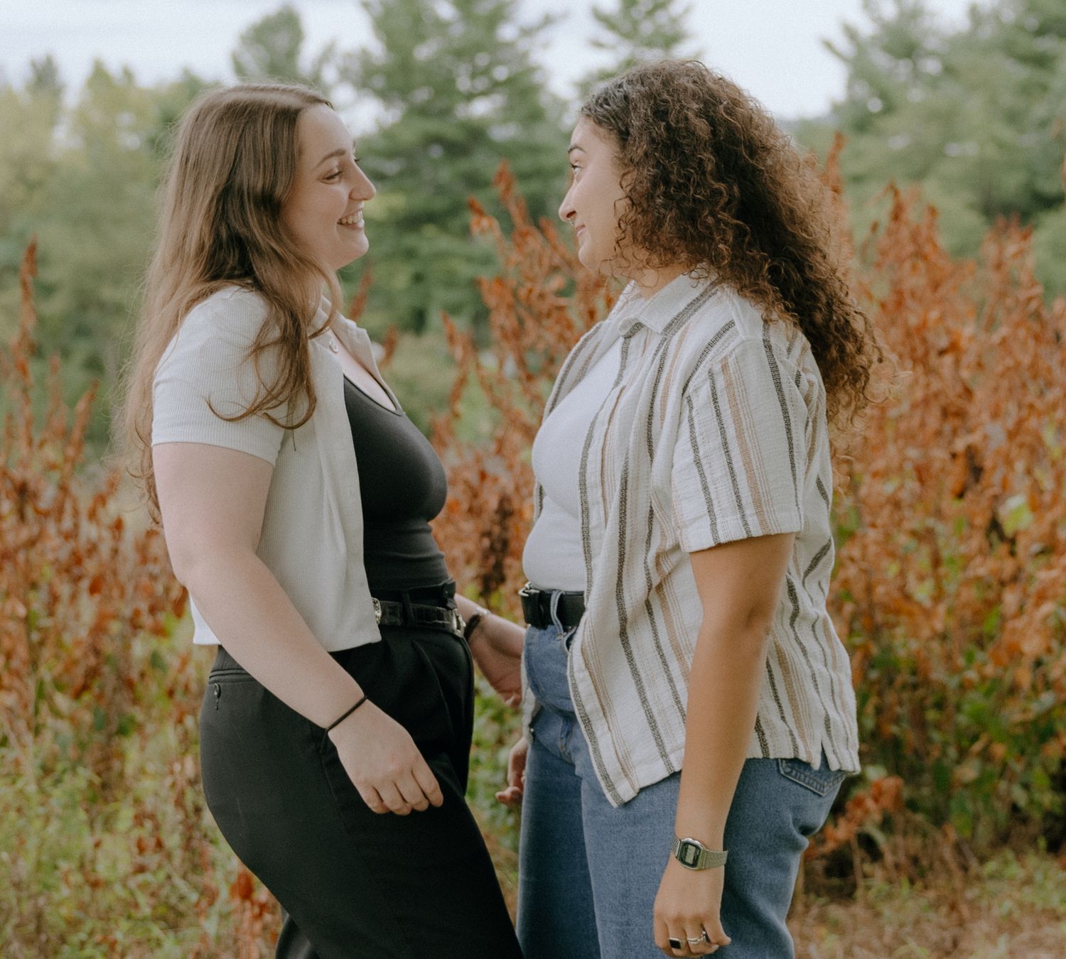 Two friends share genuine laughter during an outdoor autumn photoshoot.