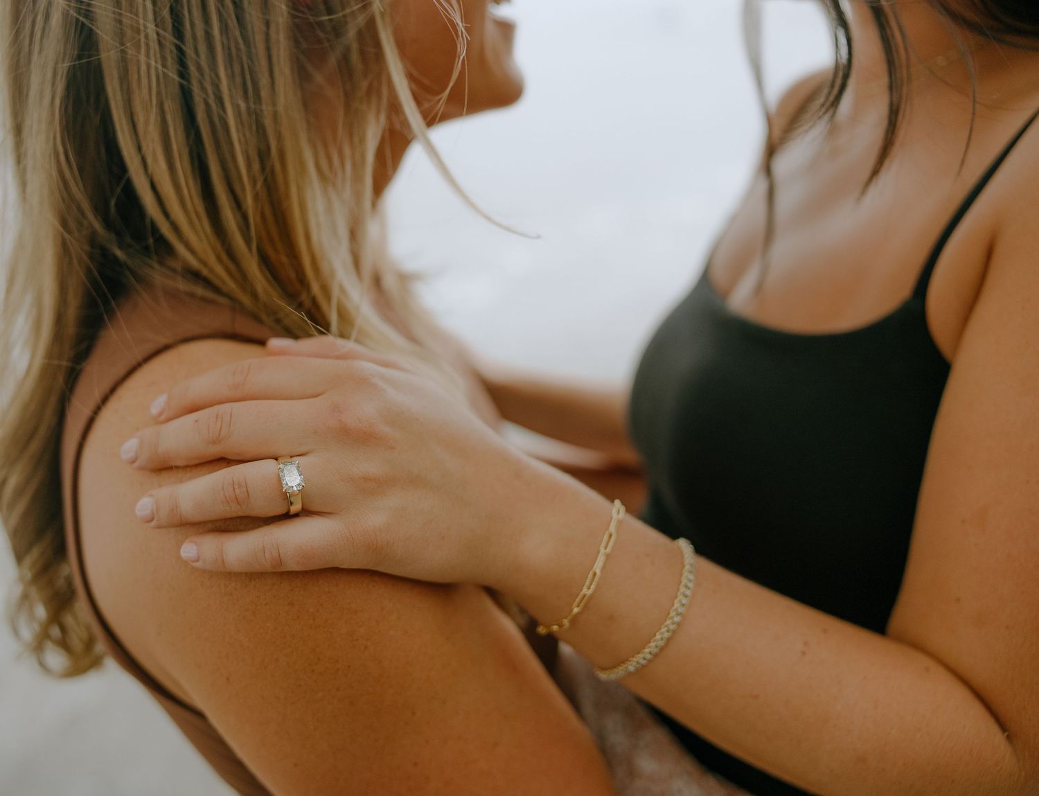 Close-up details of jewelry and hands against a soft background.