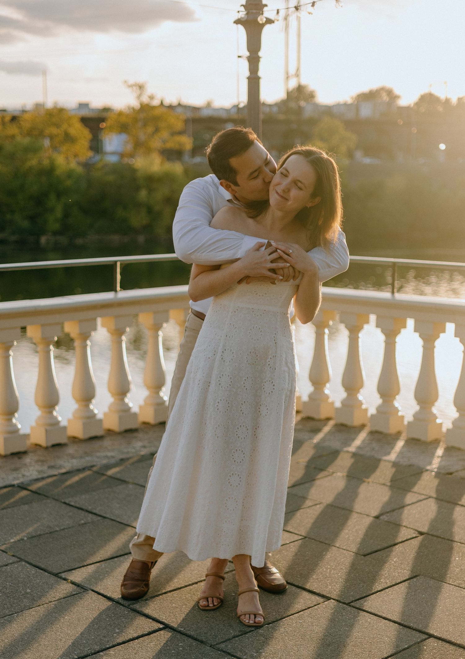 Sunset engagement photos on a white balustrade terrace with long shadows and warm lighting.