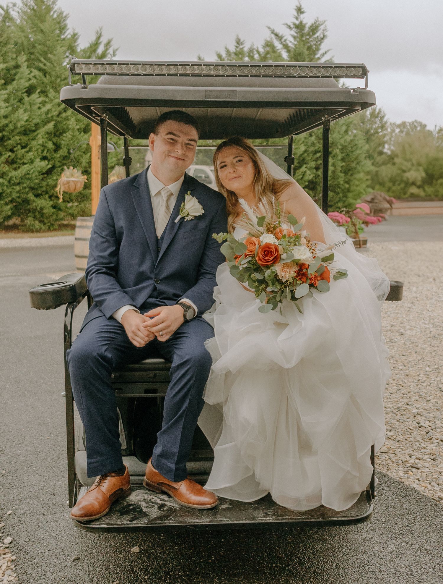 A couple sits in a golf cart on a rainy wedding day showing their feet and elegant attire.