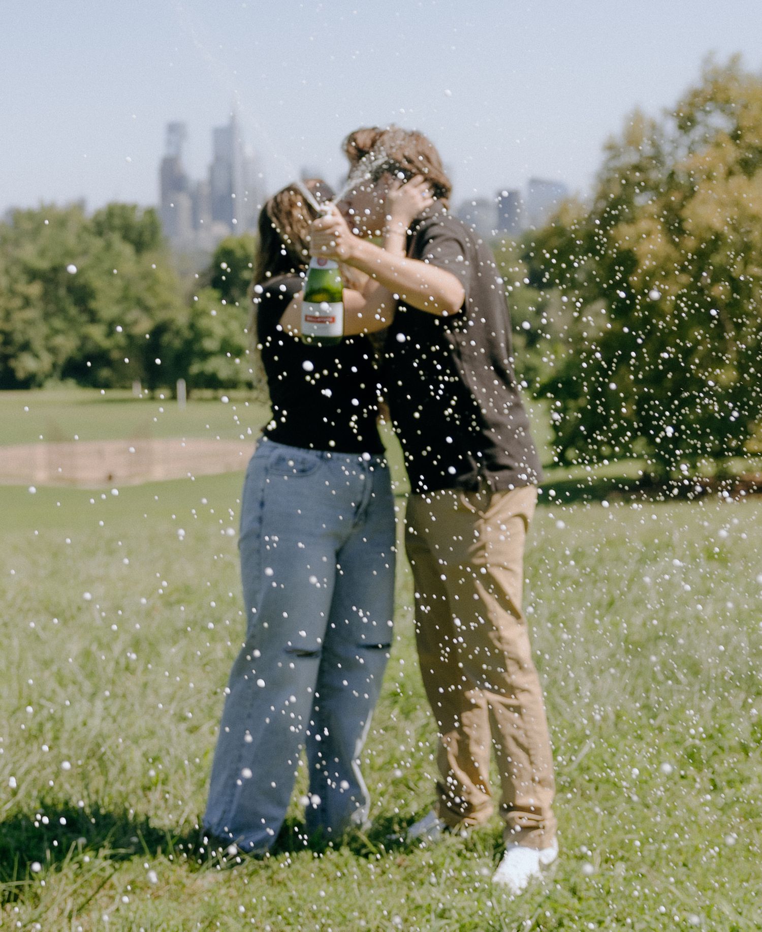 Sparkling champagne creates a magical moment between two people in a green urban park.