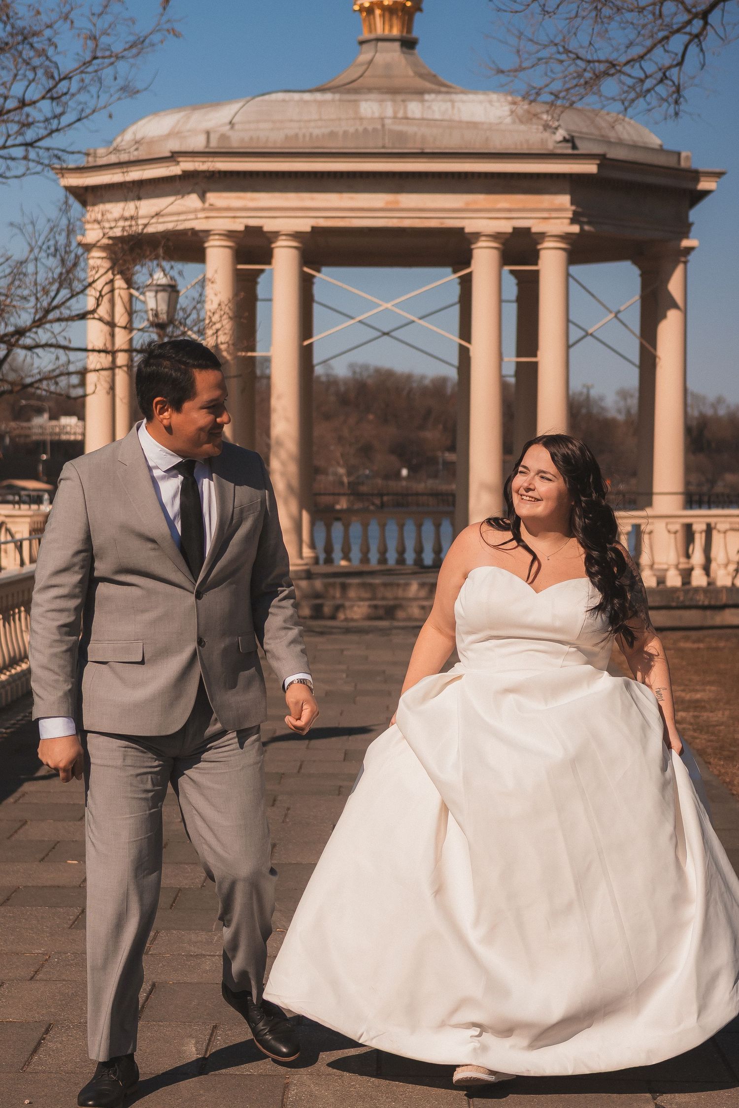 Romantic wedding photoshoot at a columned pavilion with water views in the background.