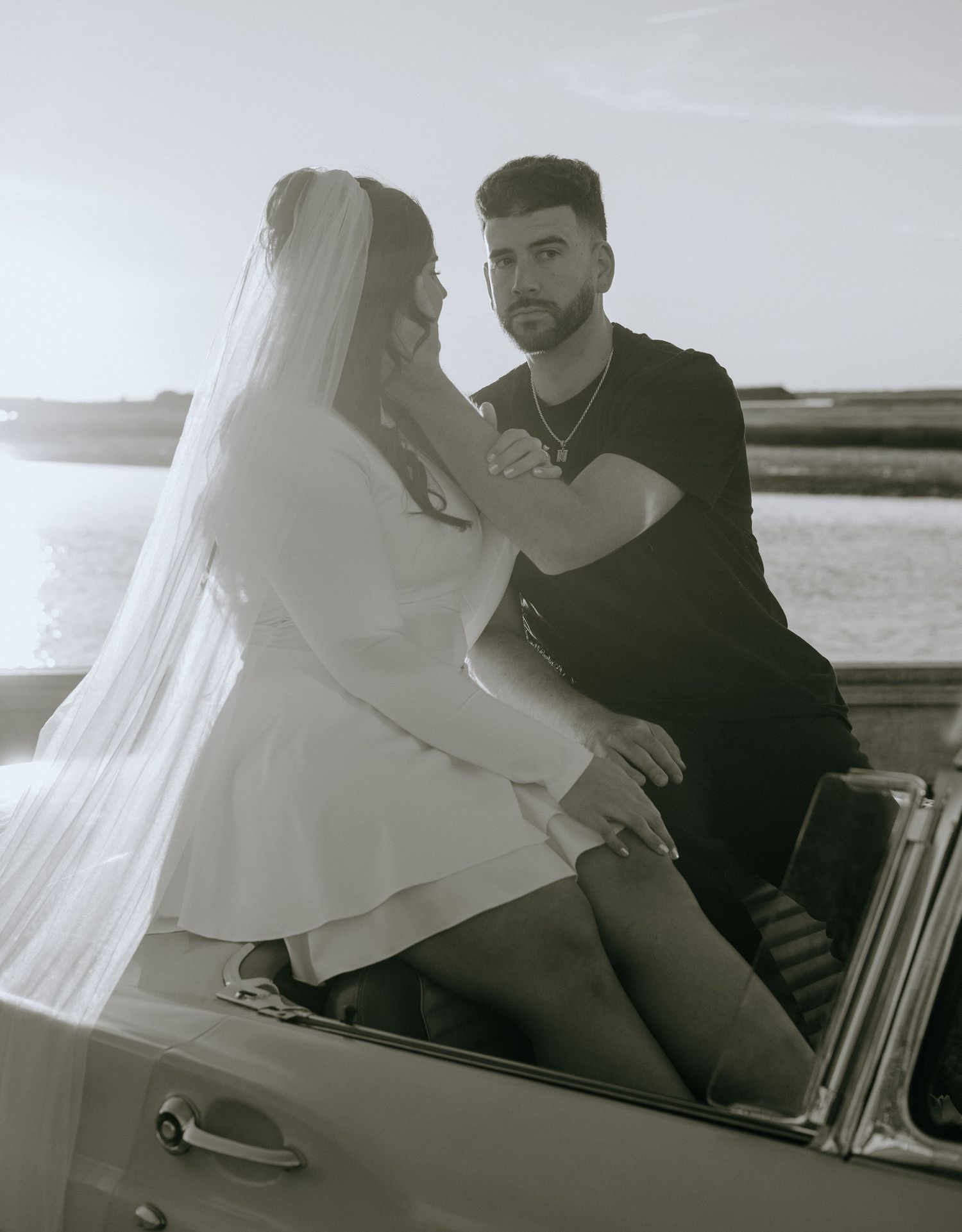 Romantic couple sitting in a classic convertible car by the water.