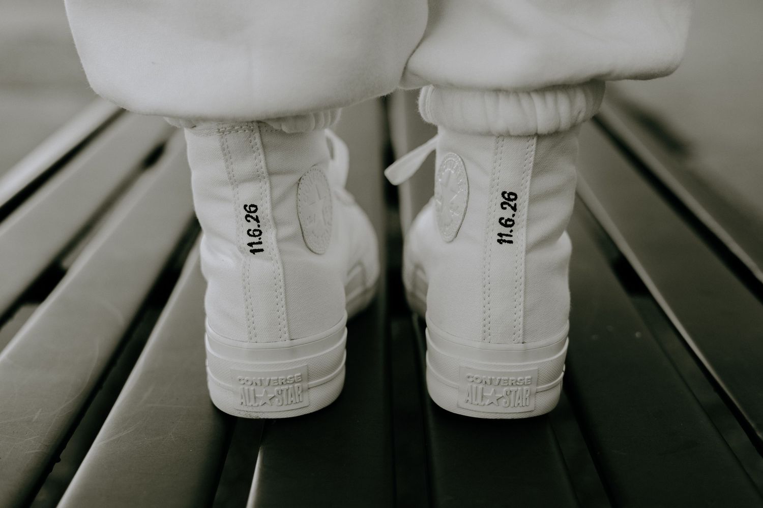 Close-up view of white sneakers on a dark surface showing minimalist footwear details.