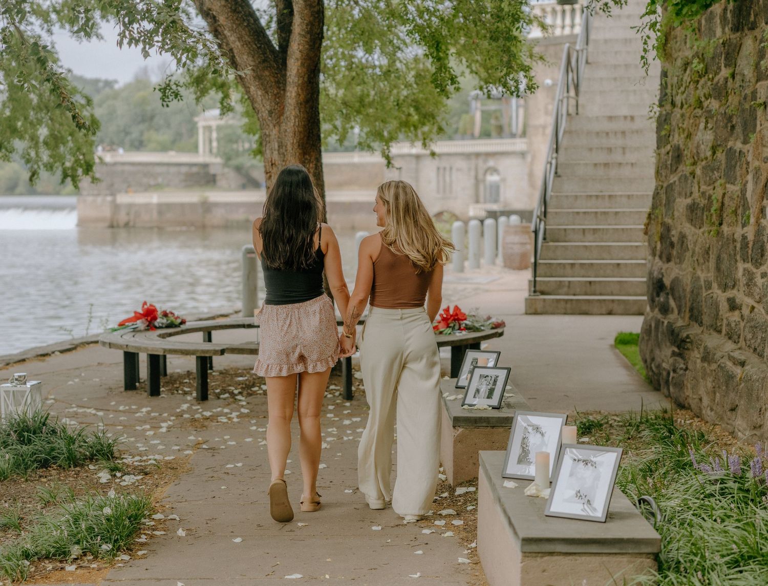 Couple walks together along a tree-lined pathway near historic architecture.