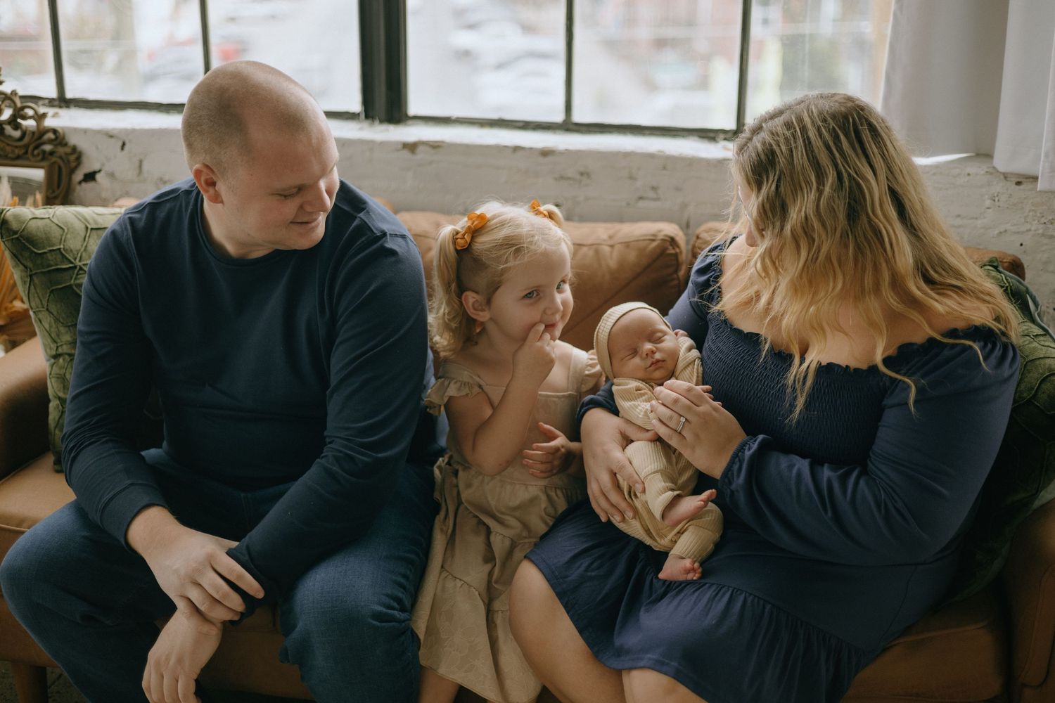 A series of intimate family moments captured in warm indoor lighting showing parents with their newborn baby.