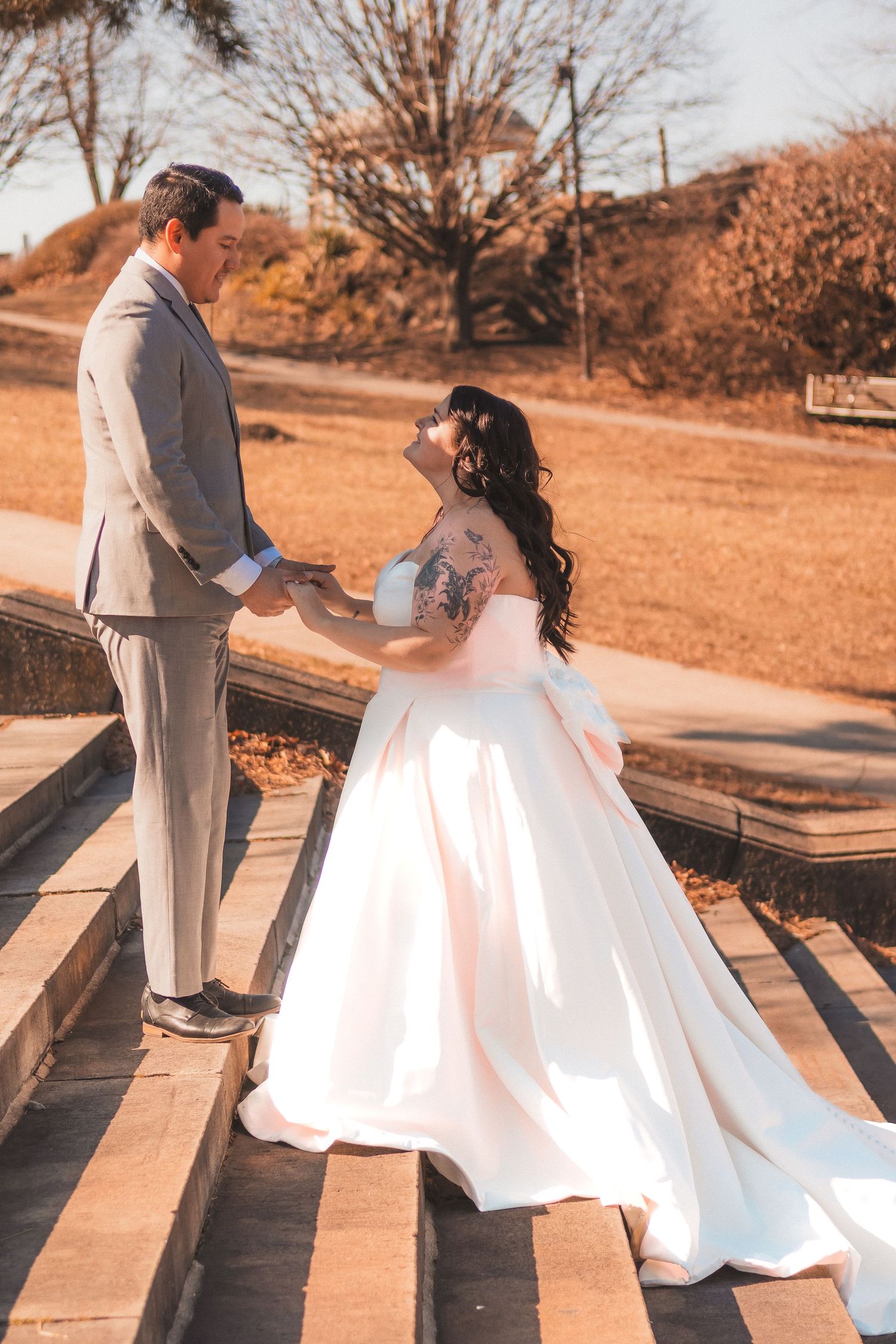 Autumn wedding scene with couple on stone steps in warm sunset lighting.