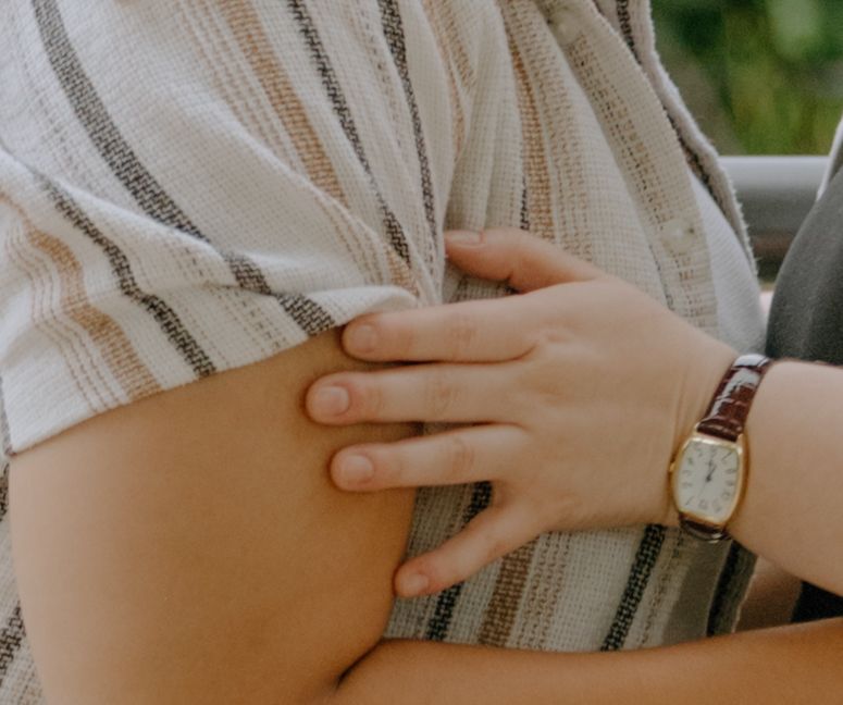 Close up of a hand resting on striped fabric with a vintage watch visible.