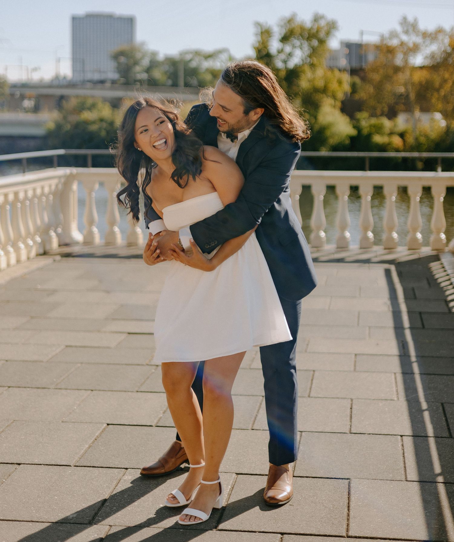 A couple performs a romantic dip dance move on an outdoor terrace with stone tiles and white balustrades.