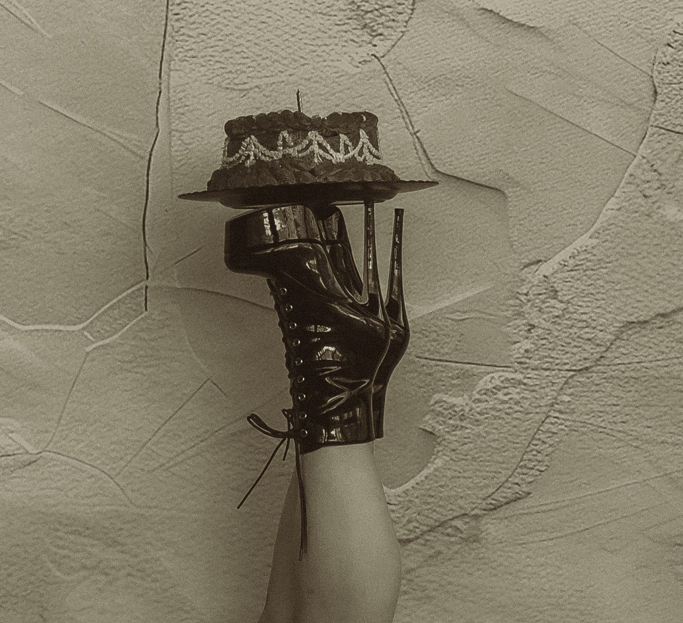 Artistic close-up shots focusing on black boots and details against textured wall.