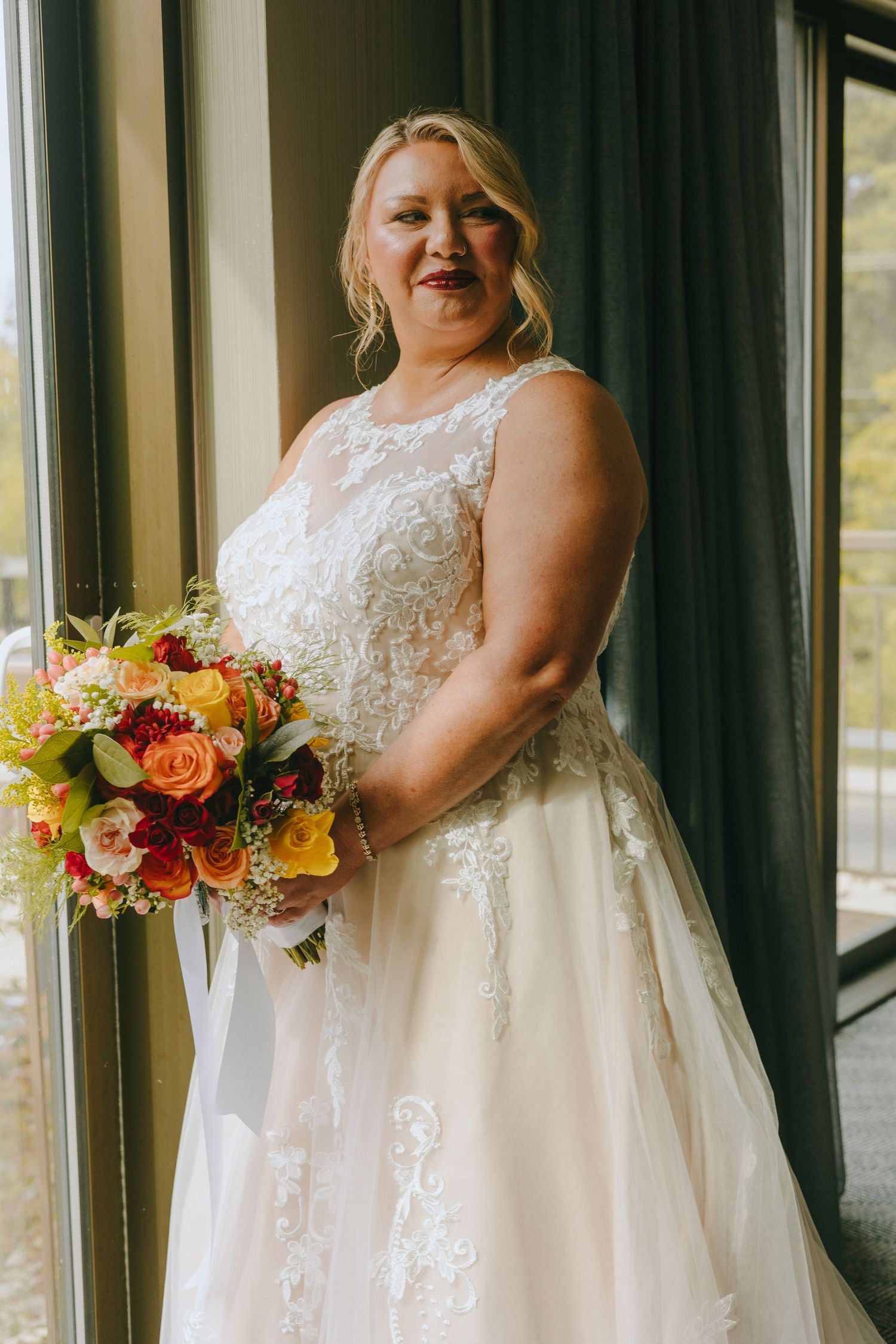 Wedding dress detail showing intricate lace bodice and flowing tulle skirt with autumn-colored bouquet.