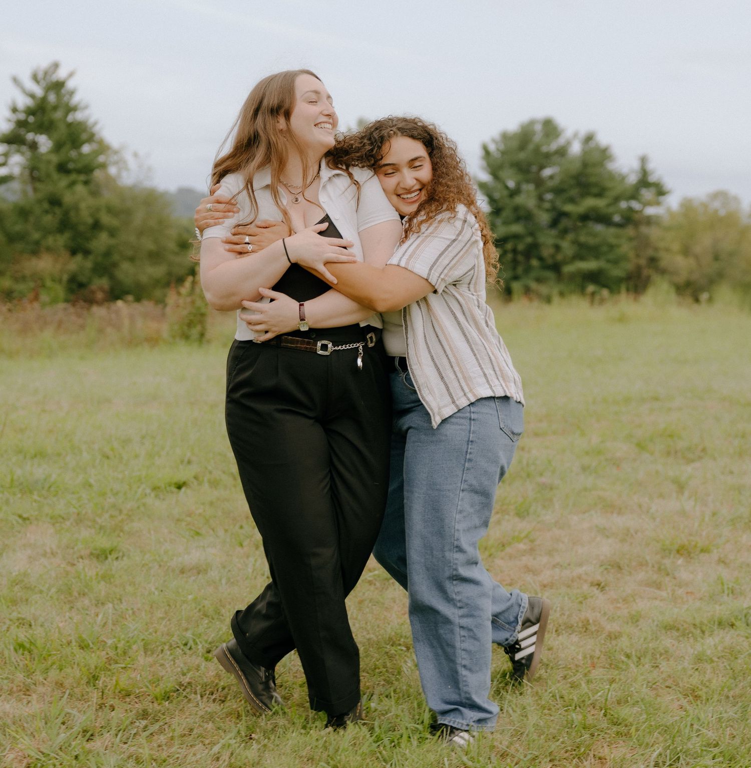 Friends share joyful moments and embraces in a sunny field.