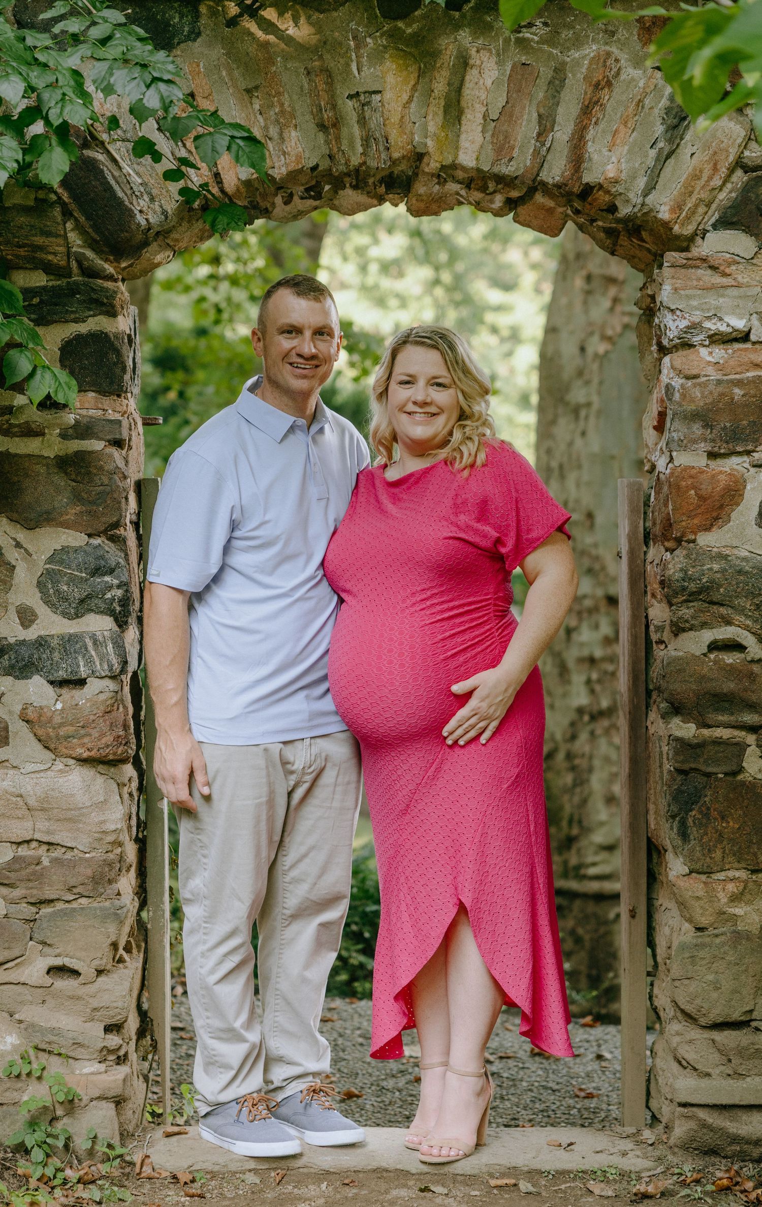 Family photoshoot under stone archway with coordinated pink and gray outfits.