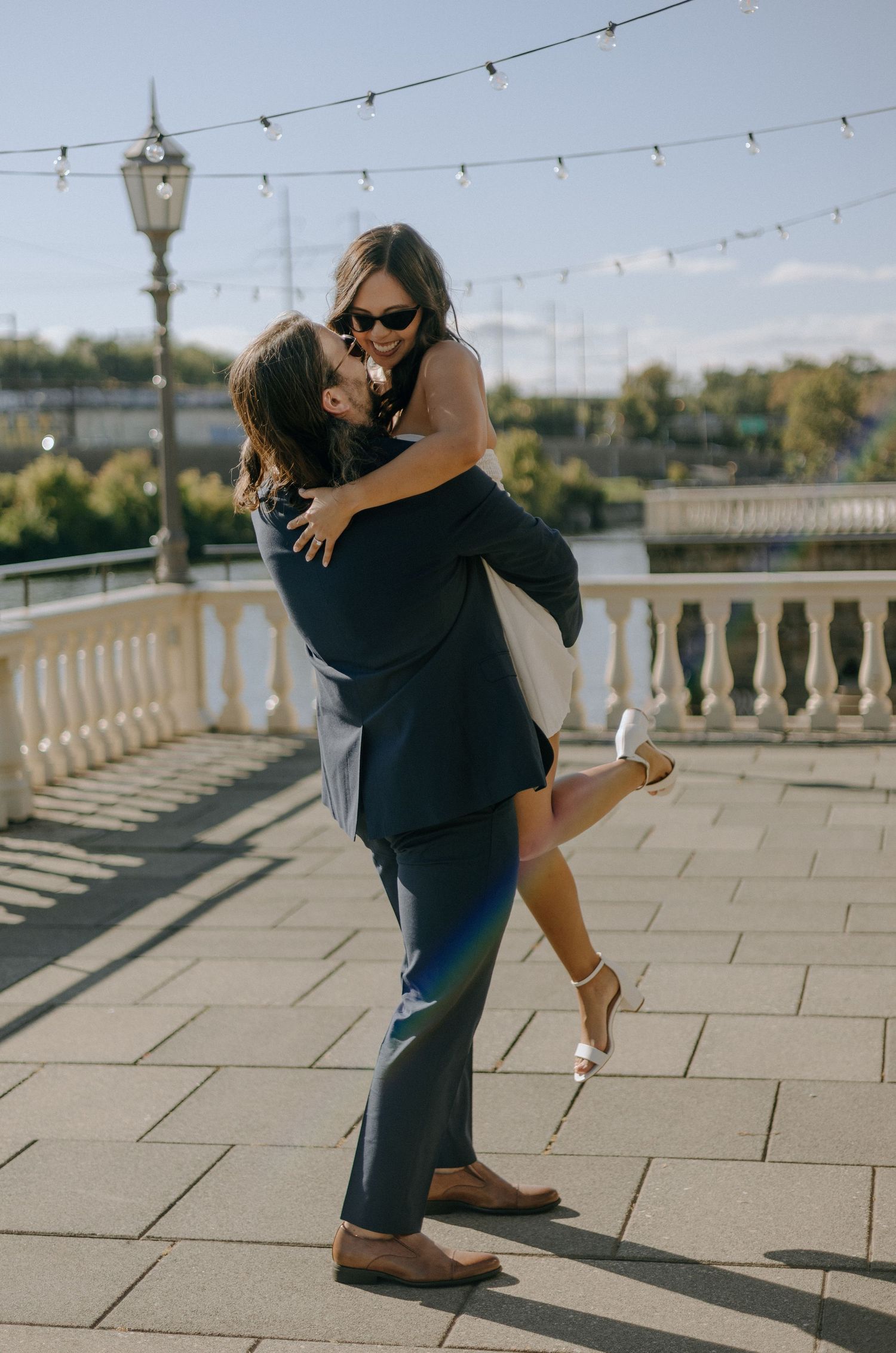 A romantic moment captured on a terrace with string lights and a vintage lamp post in the background.