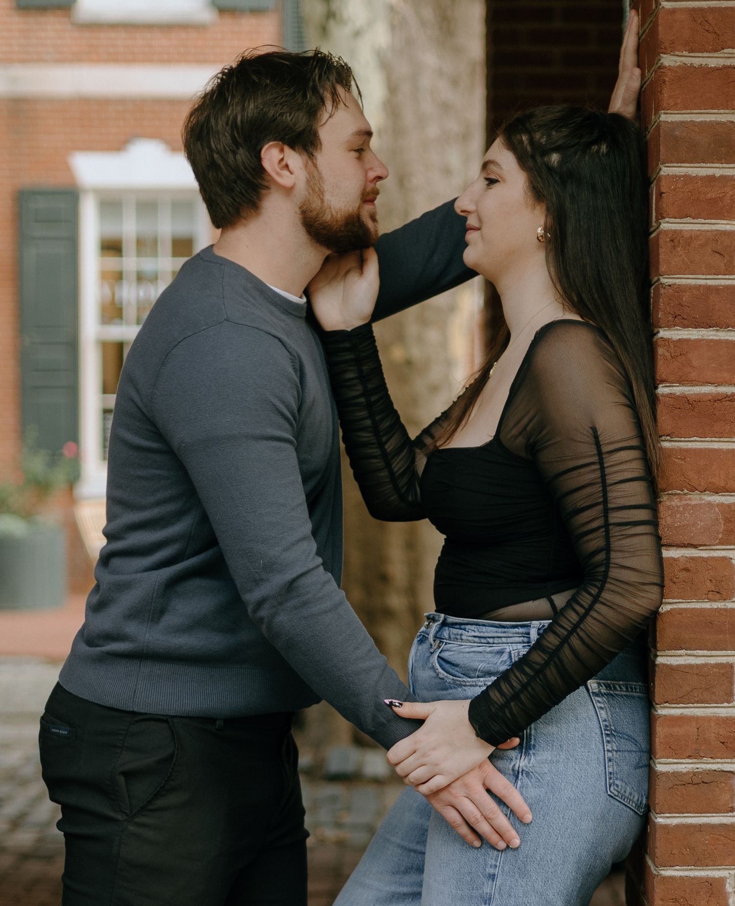 Romantic couple in casual attire sharing intimate moments against a brick wall in a series of candid photos.
