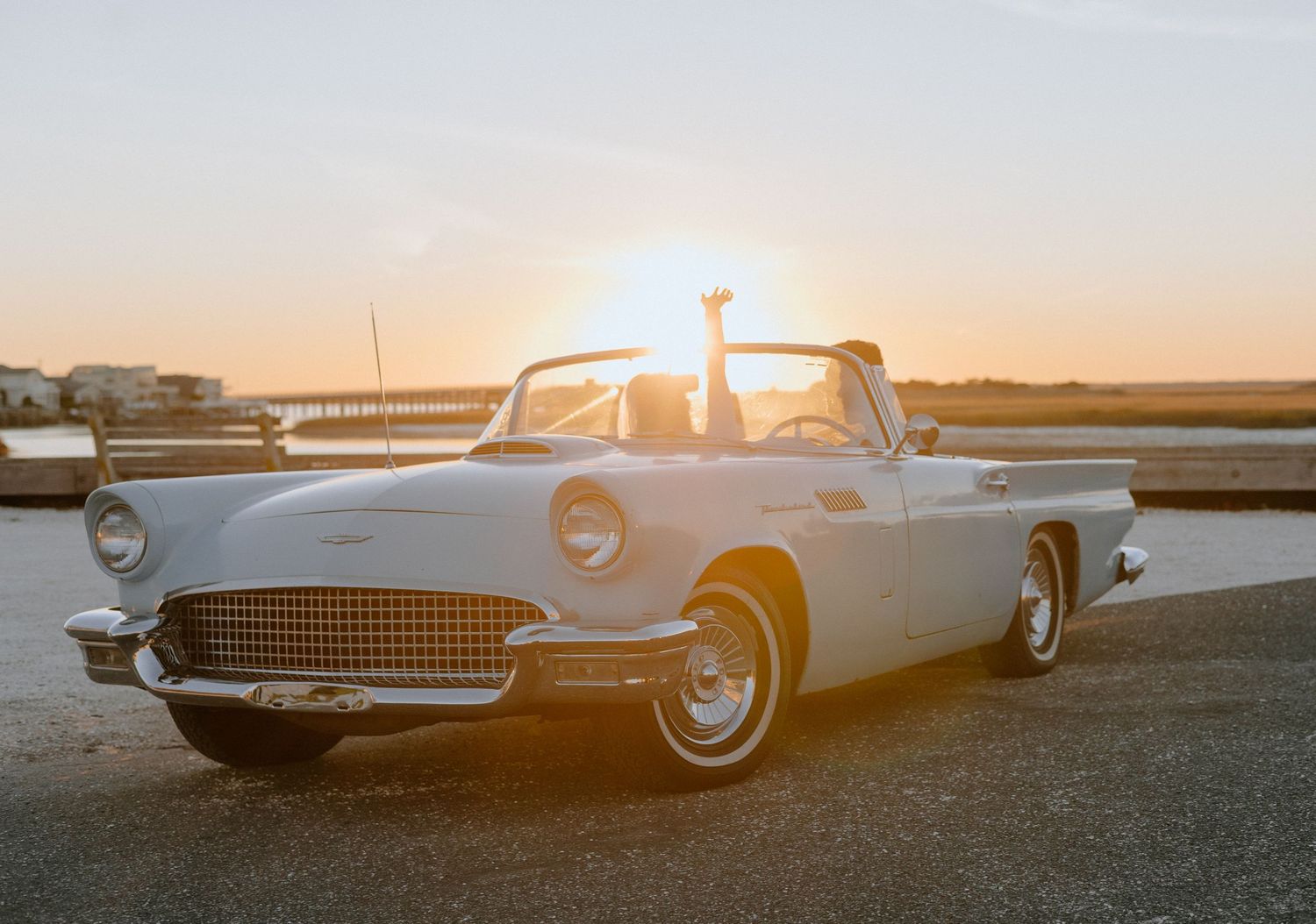 Classic vintage cars lined up against a sunset backdrop creating a nostalgic silhouette.