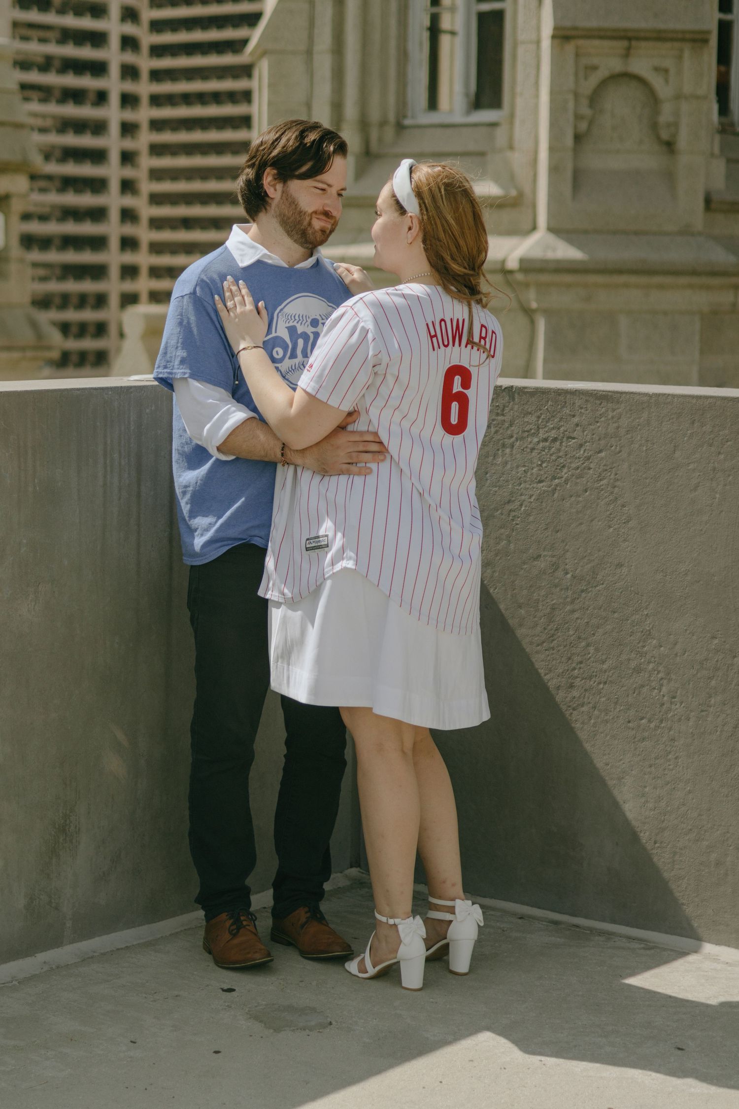 A couple in a baseball jersey embrace in a series of three romantic engagement-style photos against a stone wall.
