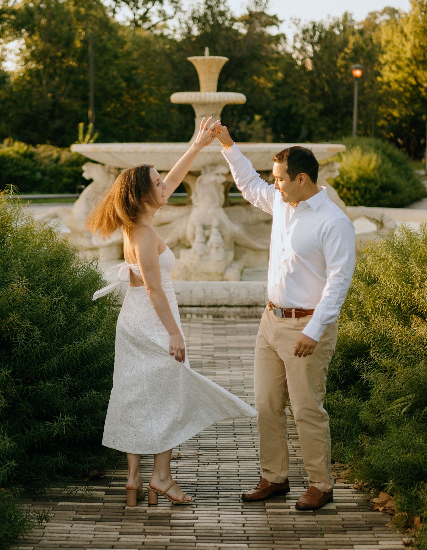A couple dances playfully on a stone patio during golden hour, creating a romantic outdoor scene.