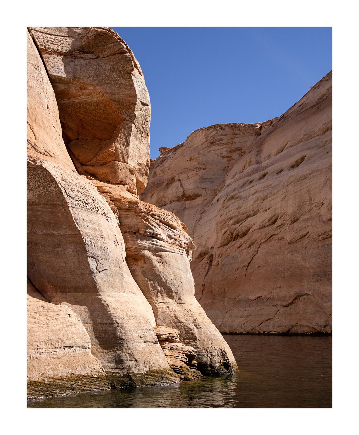 Smooth curved sandstone canyon walls reflecting in still waters at Lake Powell.