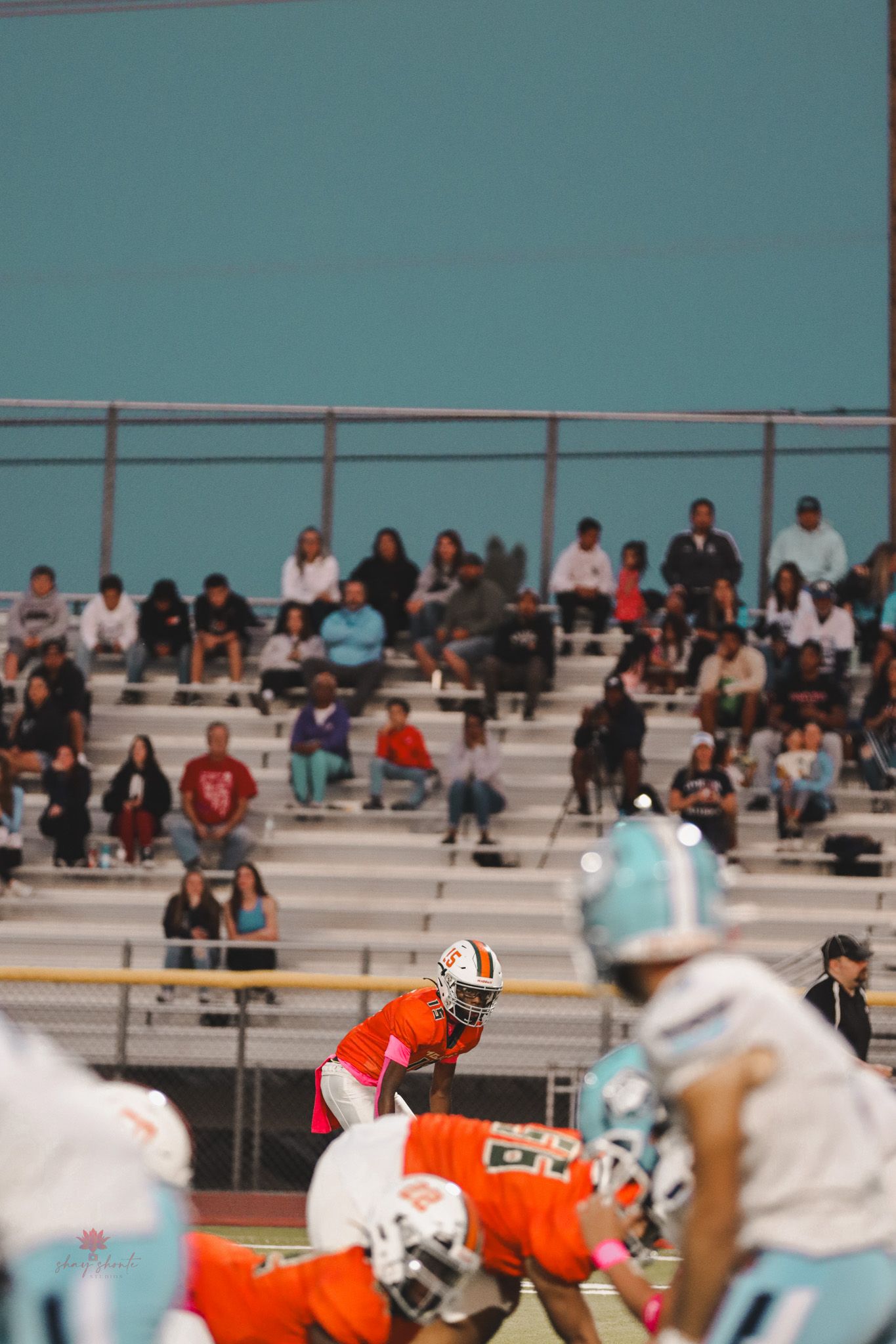 Football game in progress with crowd watching from bleachers in background.