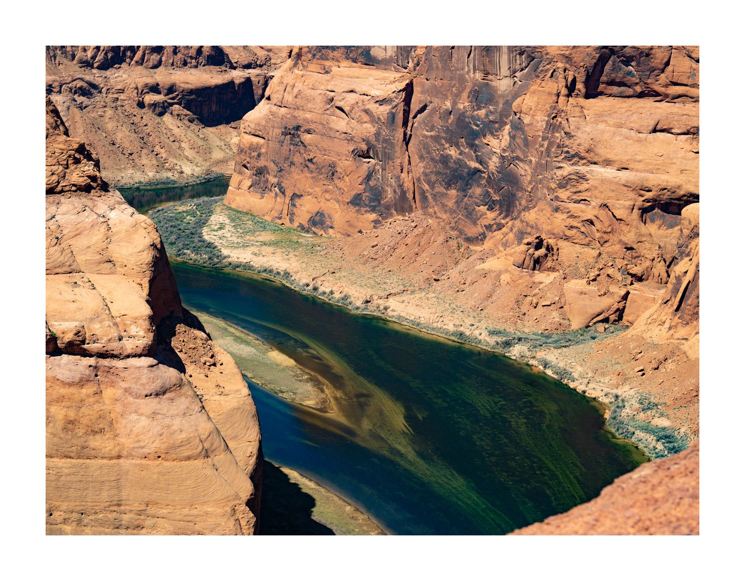 Aerial view of winding turquoise river through red rock desert canyon.