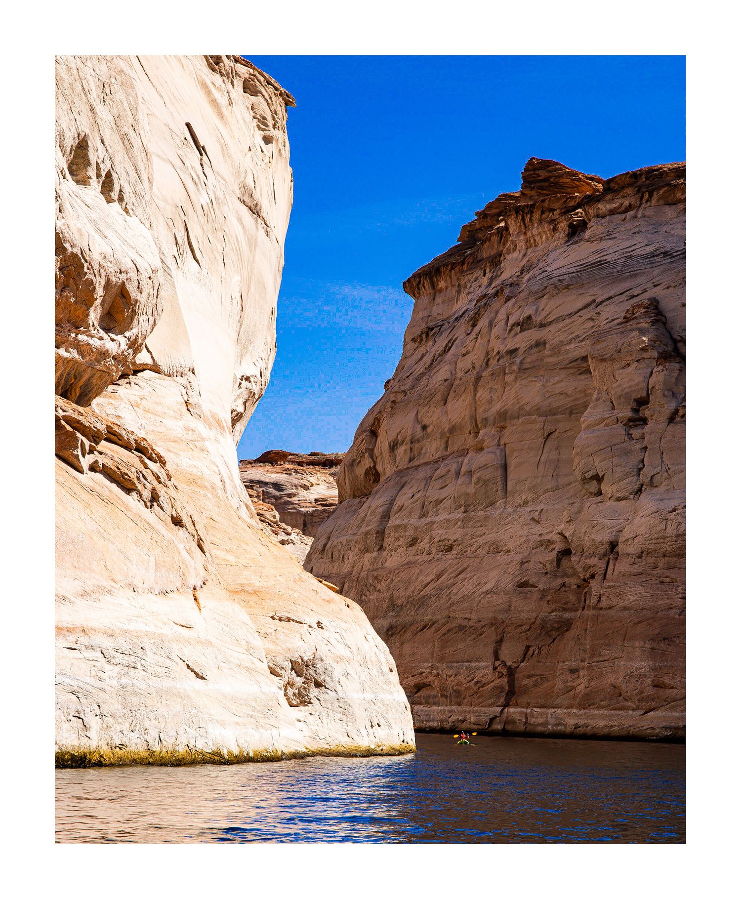 Steep white limestone canyon walls rising from blue waters in narrow gorge.