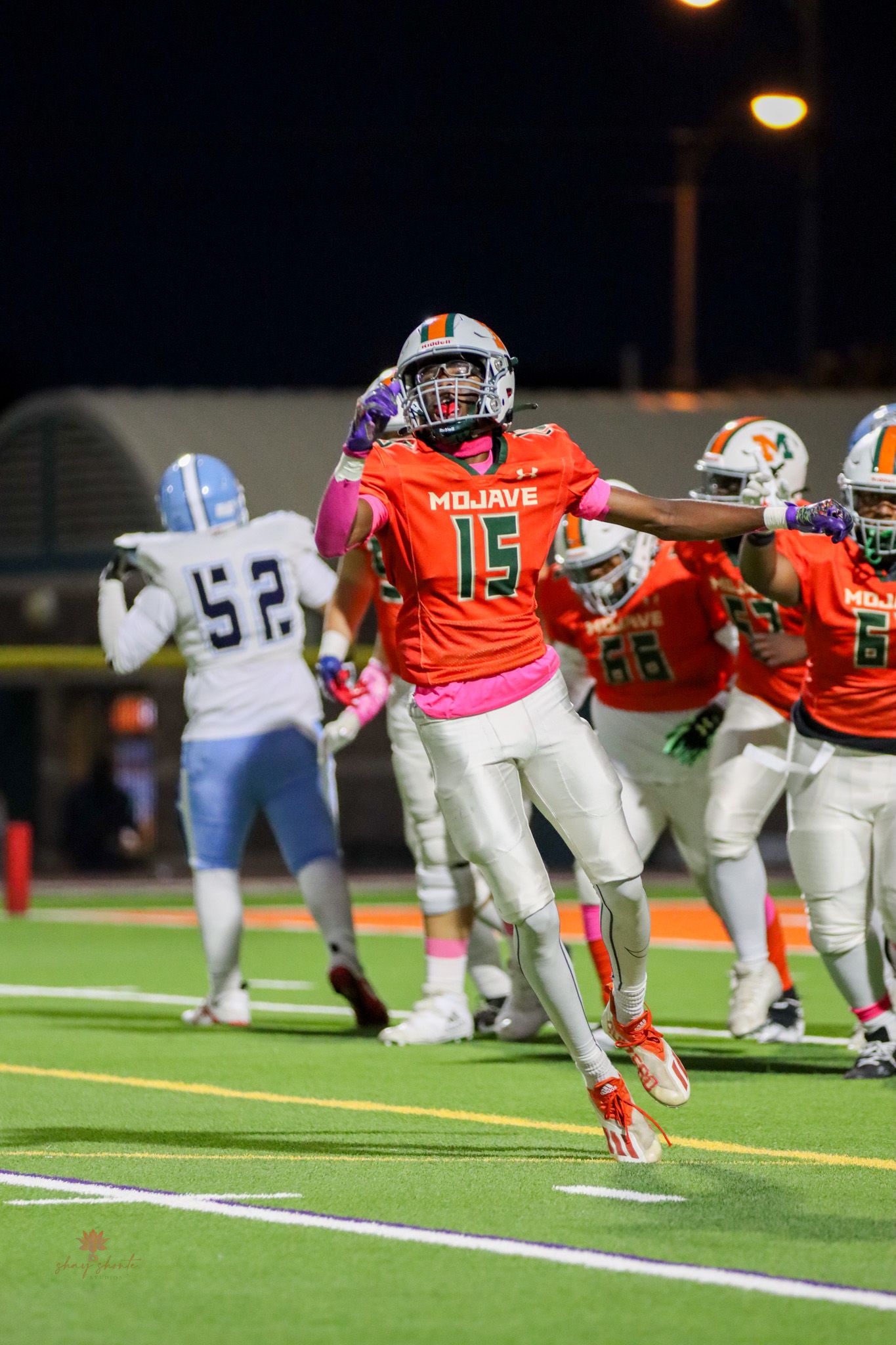 Football player in orange jersey celebrating during nighttime game.