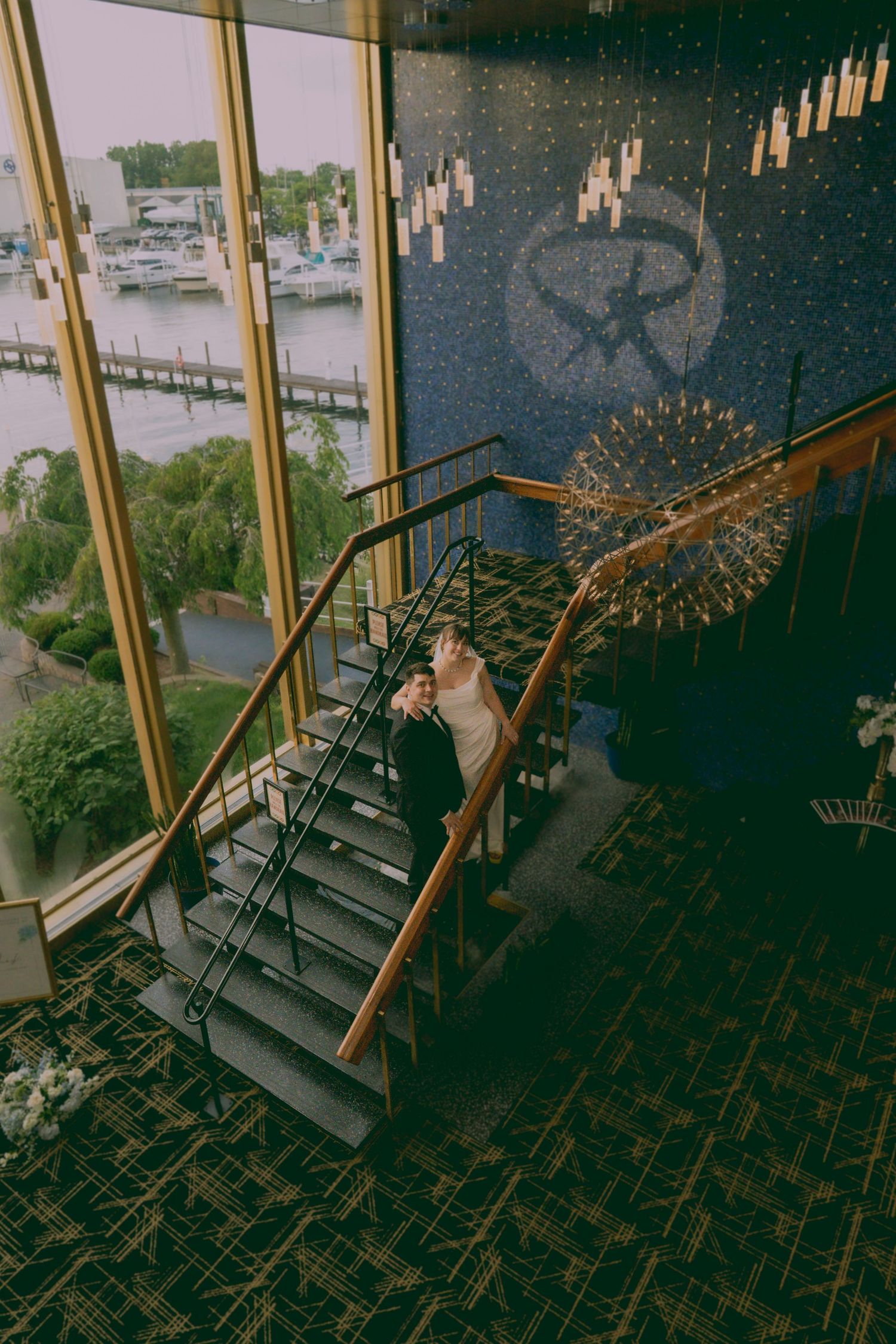 Dramatic aerial view of a spiral staircase winding down in a dark moody setting with golden railings.