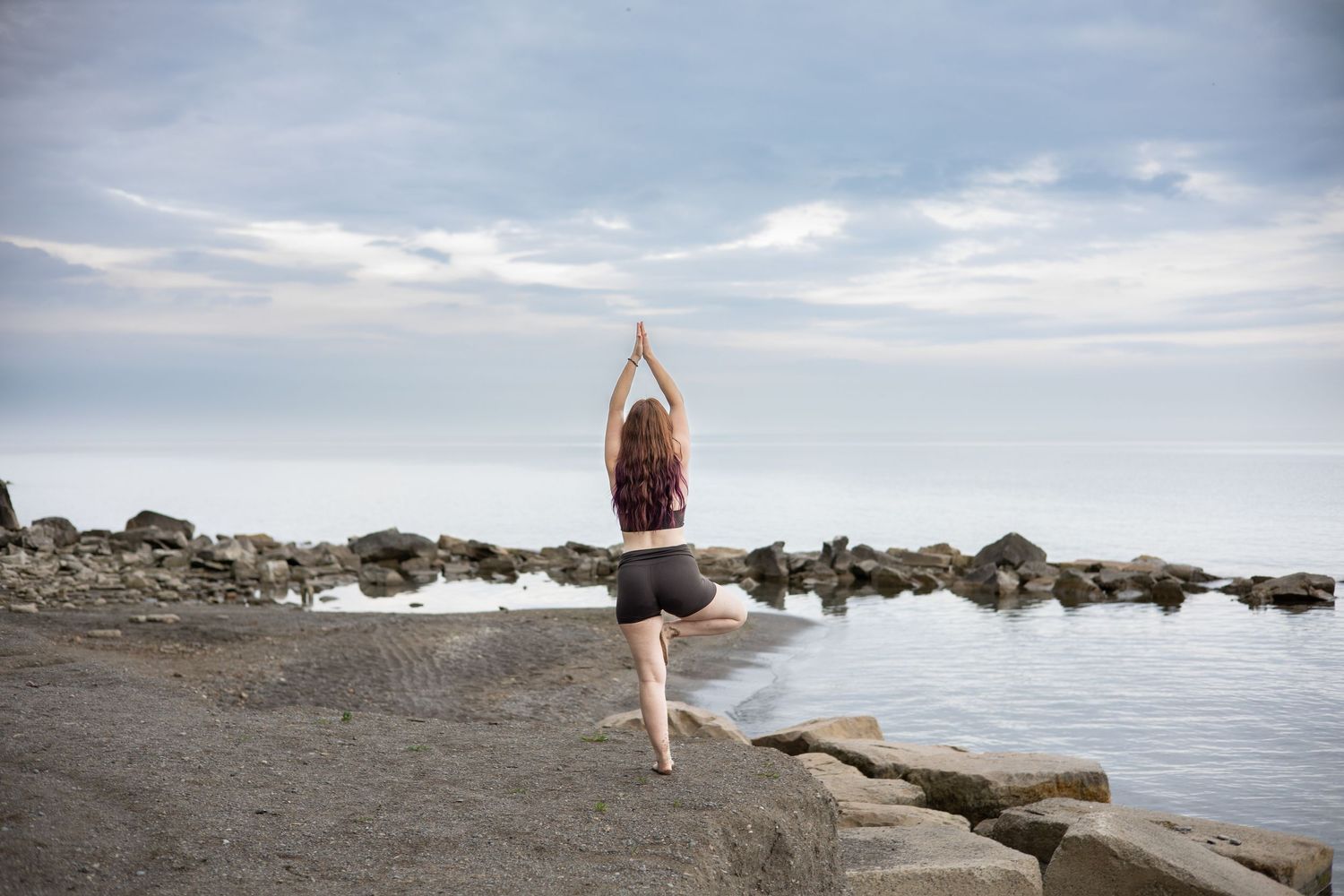 Minimalist beach photography with distant figure poses against a cloudy horizon.
