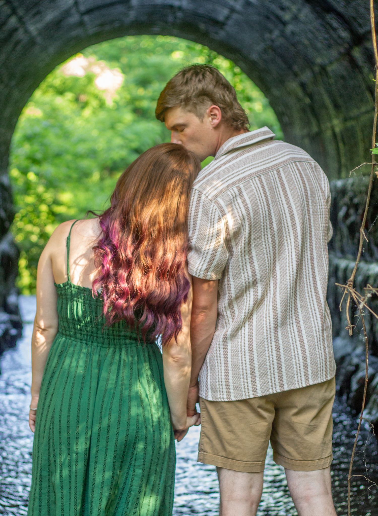 A romantic couple sharing an intimate moment under a stone tunnel arch. During a Couples session