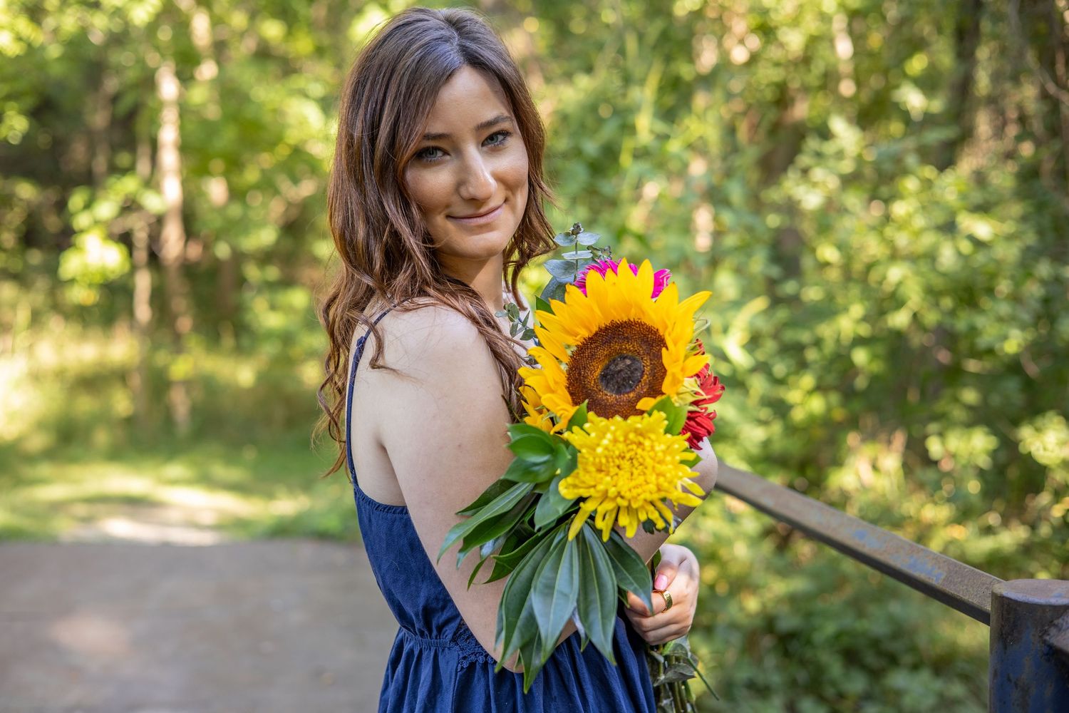 Woman smiling on bridge with flower bouquet during Portrait session