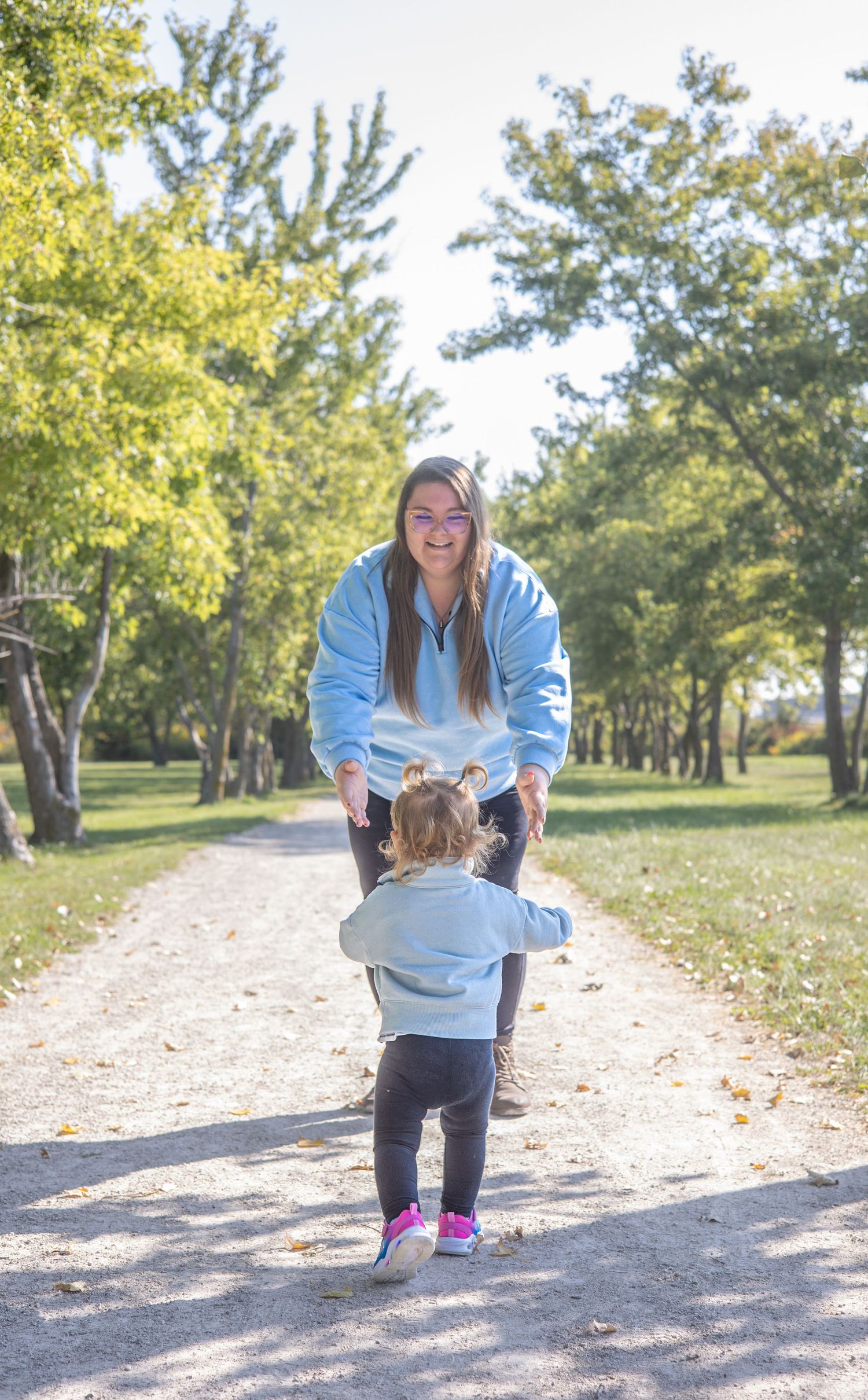 A heartwarming moment between parent and child on a tree-lined path. During Family session