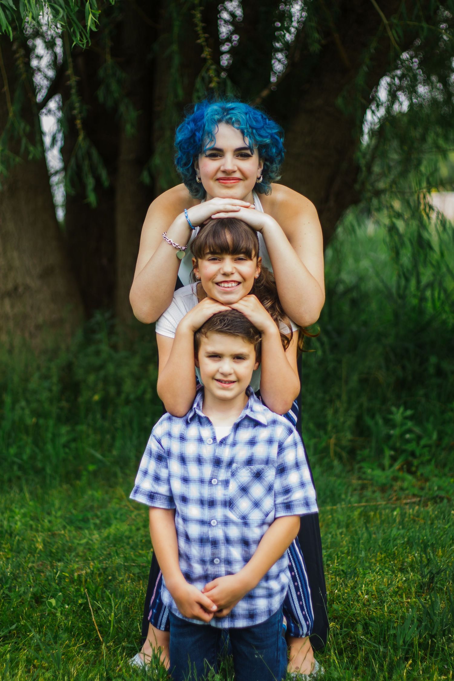 Playful outdoor portrait in wooded setting with bright blue hair and plaid shirt.