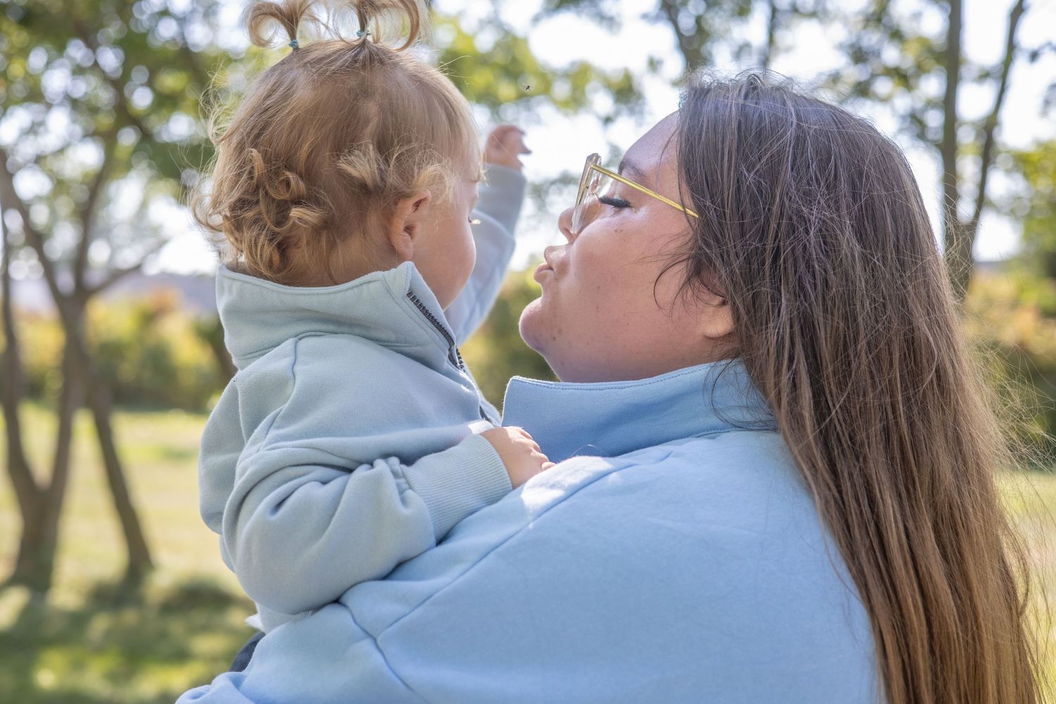 Close-up of affectionate interaction between parent and child in blue hoodies.