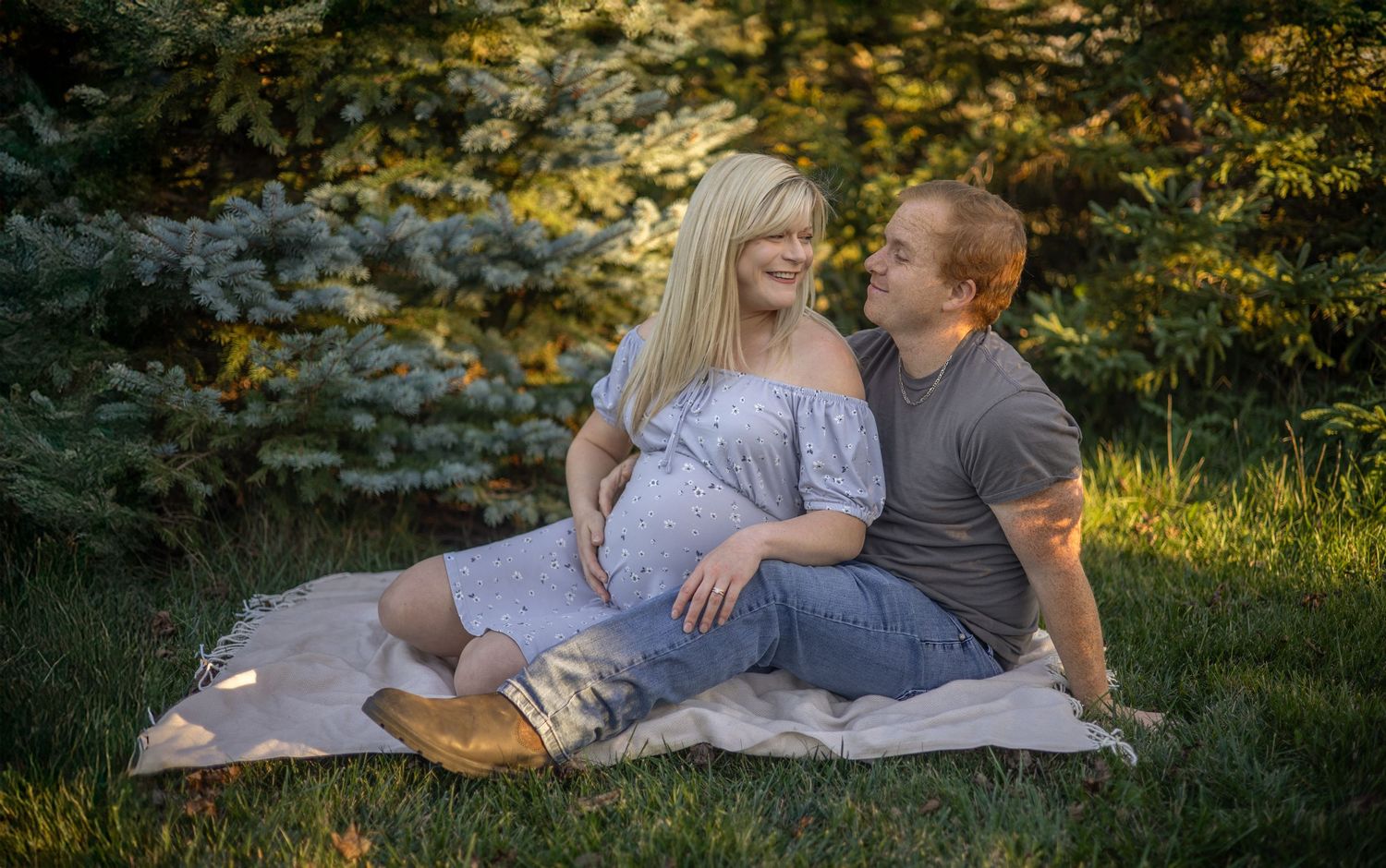 Couple lounging on blanket in grass during golden hour photography session.