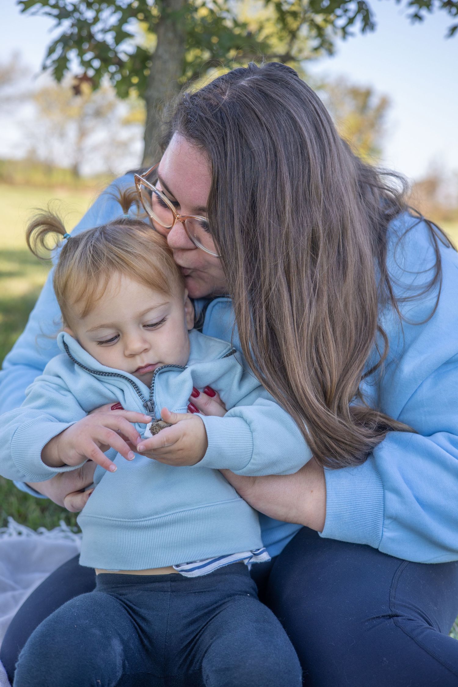 Tender moment captured between parent and child wearing matching light blue sweatshirts.