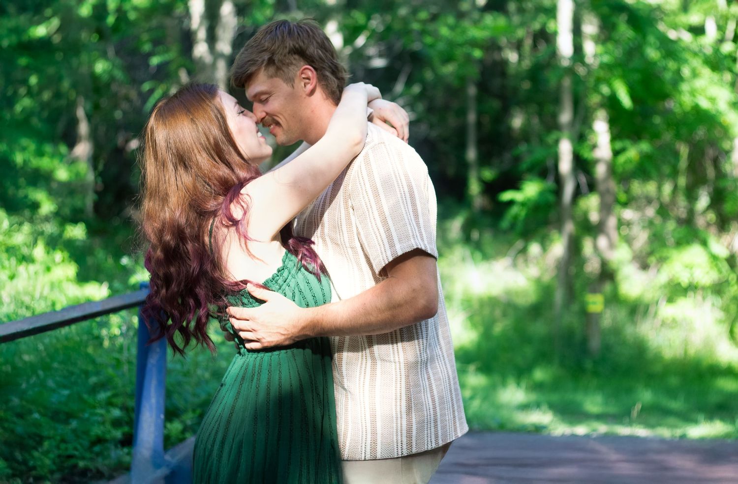 Romantic couple embracing in lush green forest setting during summer.