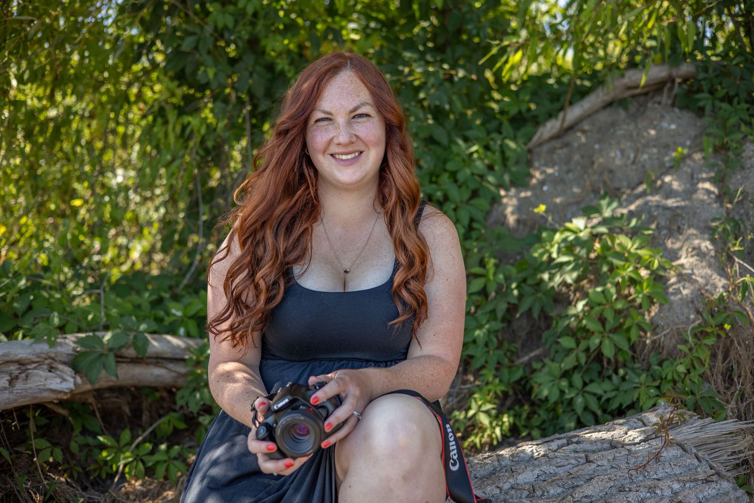 Person sitting on a rustic wooden bench in a lush green forest setting.