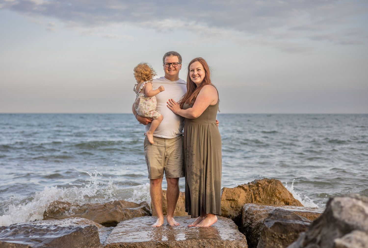 Family portrait session at a beach during sunset with waves crashing in the background.