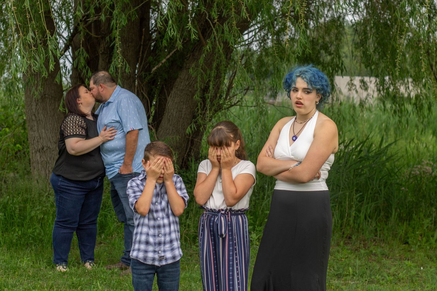 Casual outdoor family photo session under drooping willow branches.