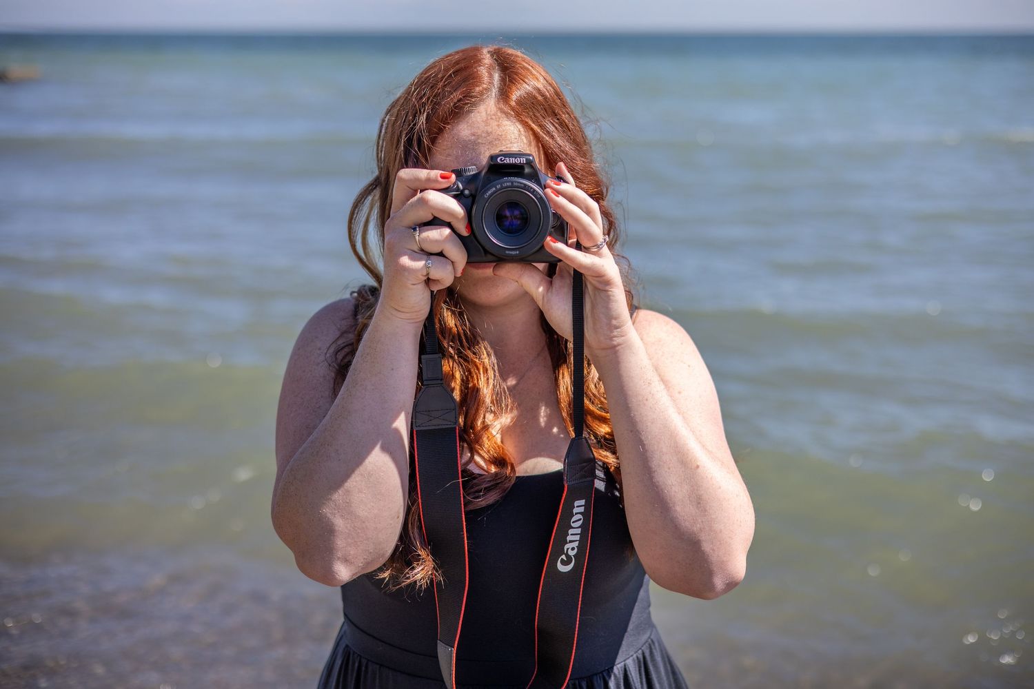 Someone takes photos with a camera by a scenic lake on a bright day.