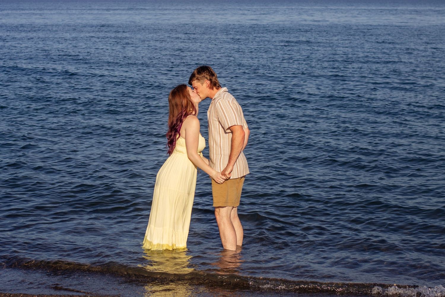 Romantic couple photoshoot in water during sunset with artistic silhouettes.