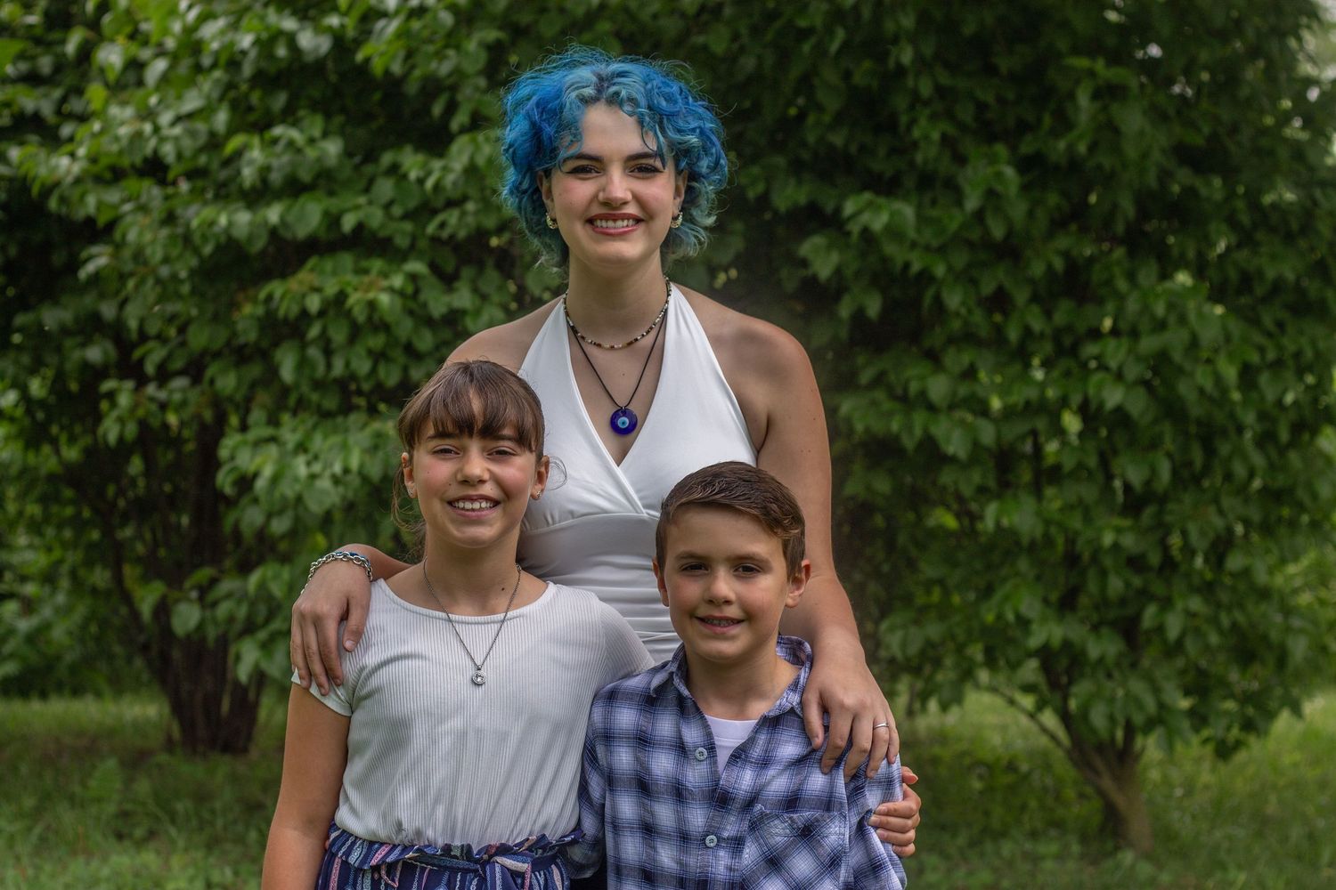 Group portrait taken outdoors against lush green foliage background.