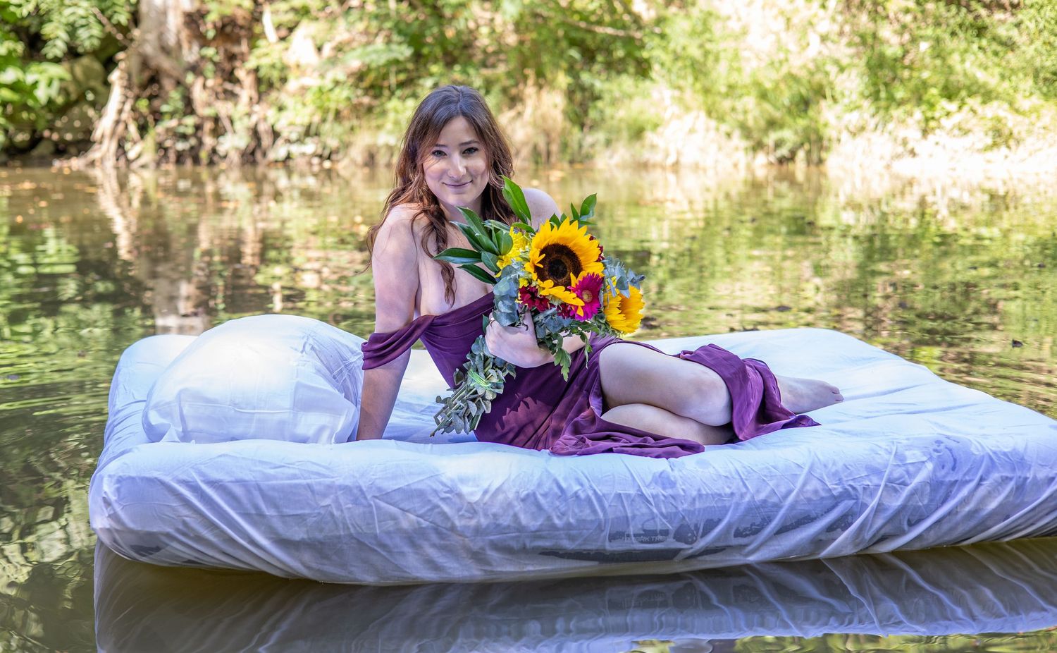Person relaxing on white bedding with sunflowers in outdoor setting.