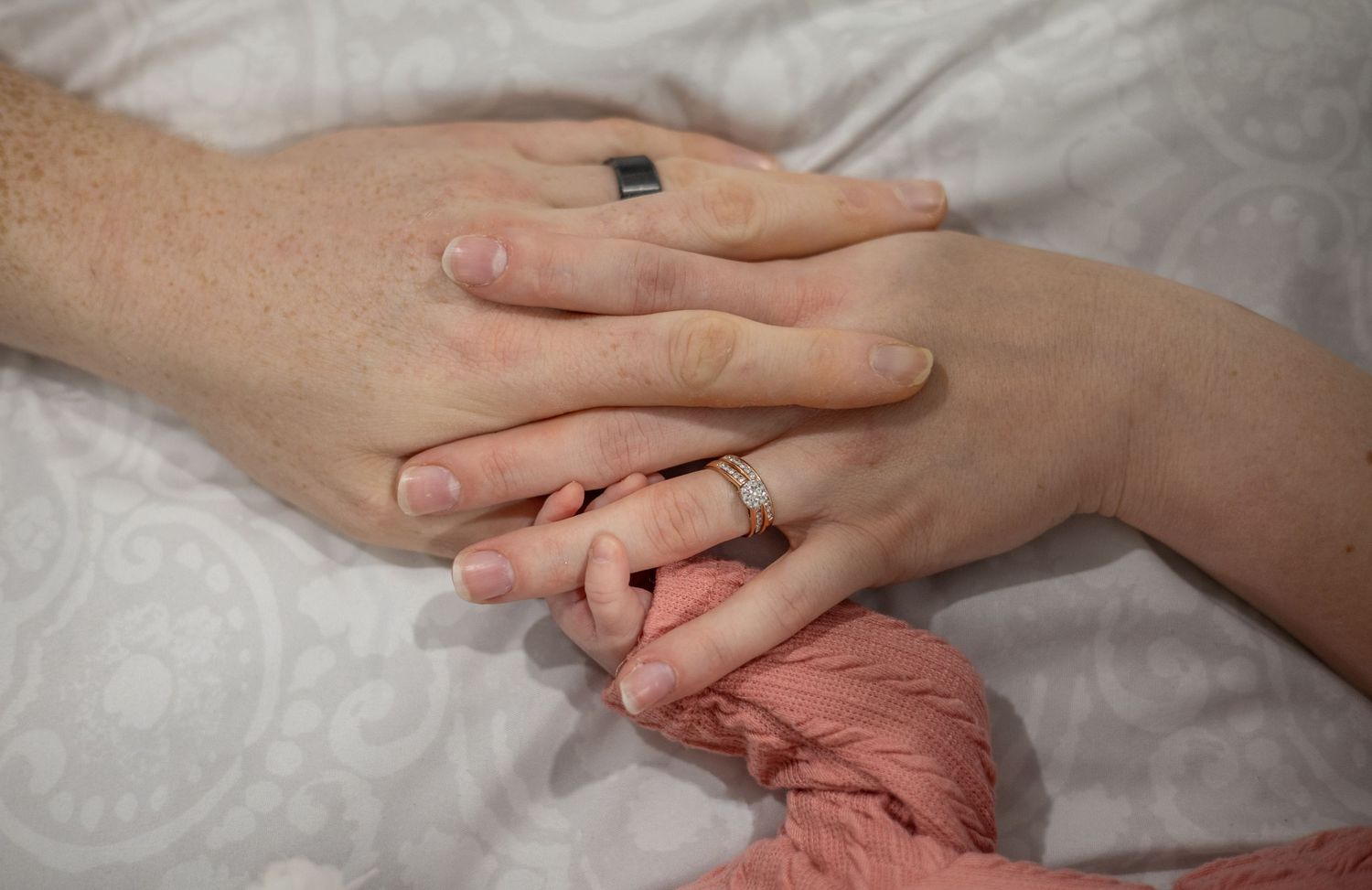 A series of hands touching and holding each other against a soft white background in a comforting gesture.