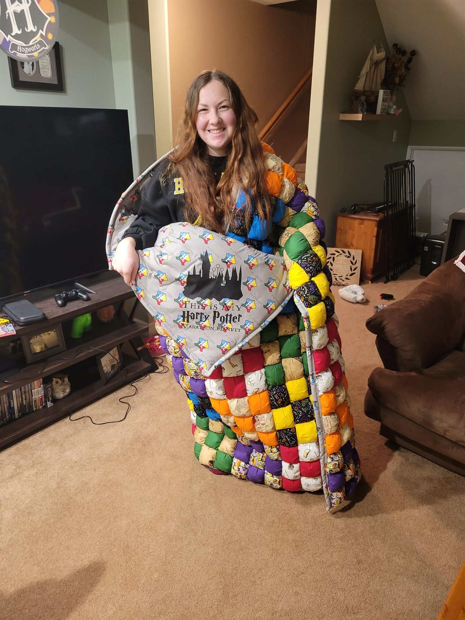 Colorful patchwork Harry Potter themed blanket displayed on brown carpet in living room.